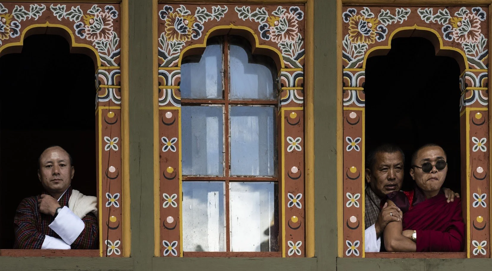 נזירים בודהיסטים מציצים מתוך חלונות מצוירים במנזר — בהוטן