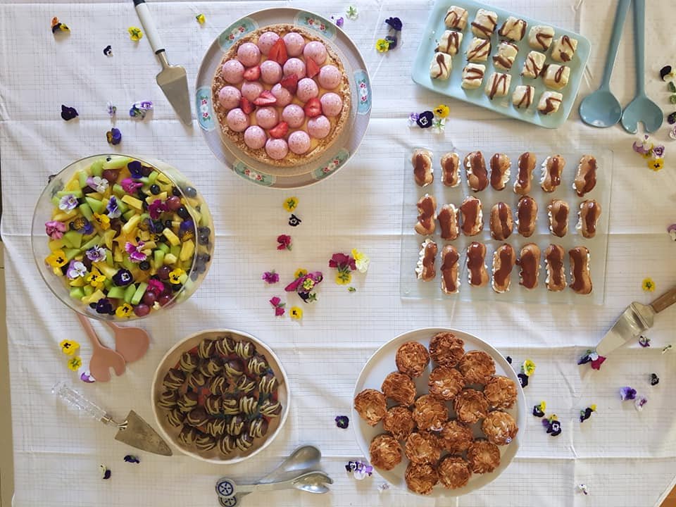 שולחן קינוחים שלם מפוזר בפרחי מאכל – מסיבת גן מתוקה מצולמת מלמעלה לפני שמישהו מעז לקחת את הביס הראשון
