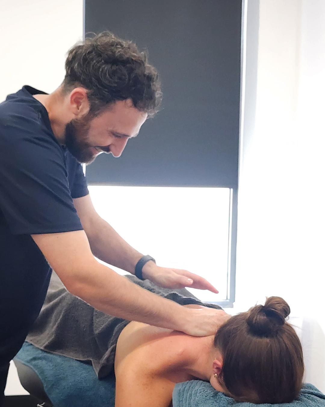 A chiropractor giving a gentle massage or adjustment to a woman lying face down on a treatment table in a clinic.
