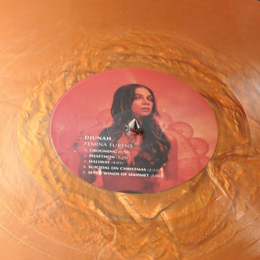 Close-up of a vinyl record spinning on a turntable, with a pink label featuring a woman's photo and song titles.