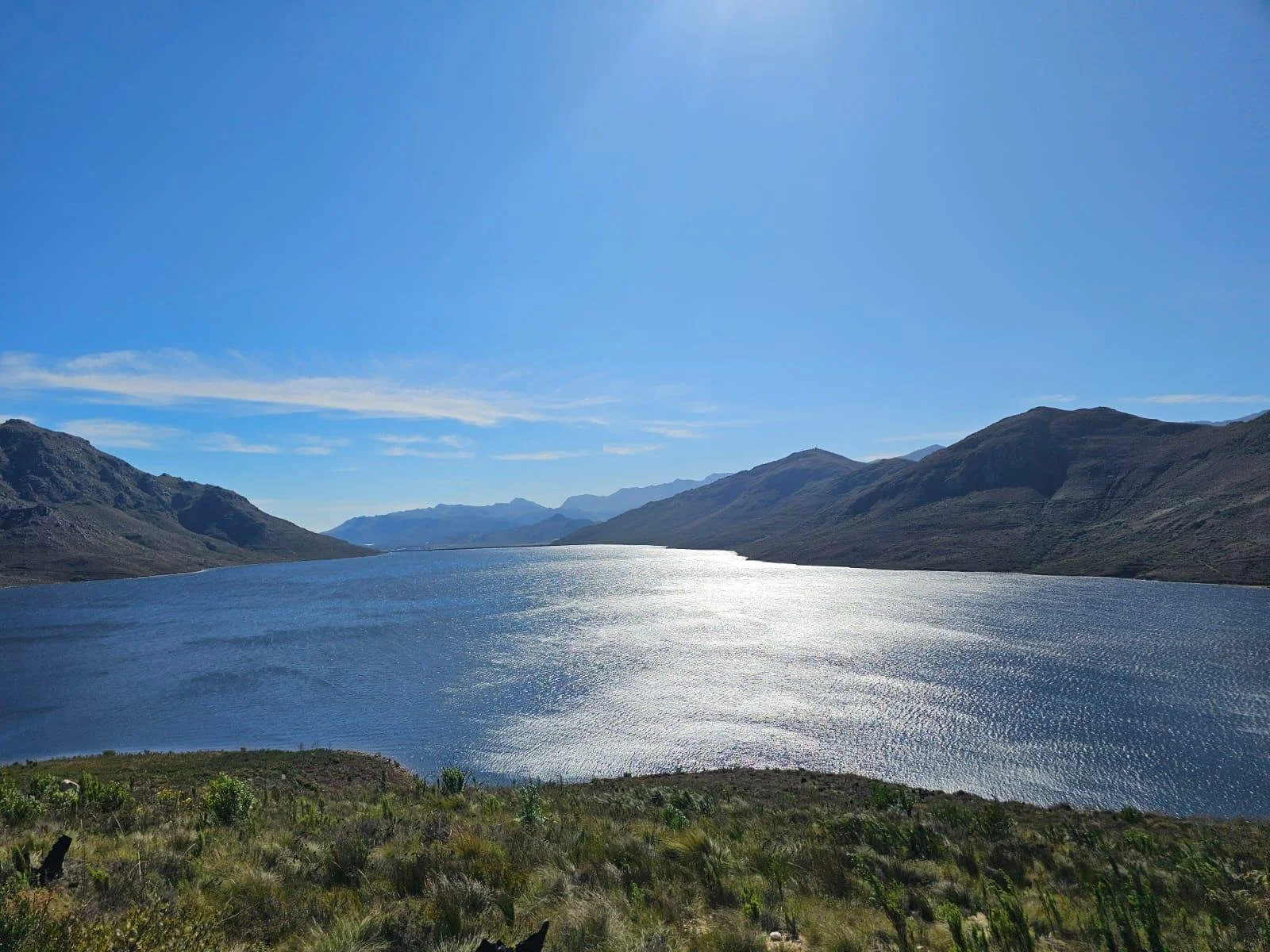 Scenic view of a lake surrounded by mountains under a clear blue sky.