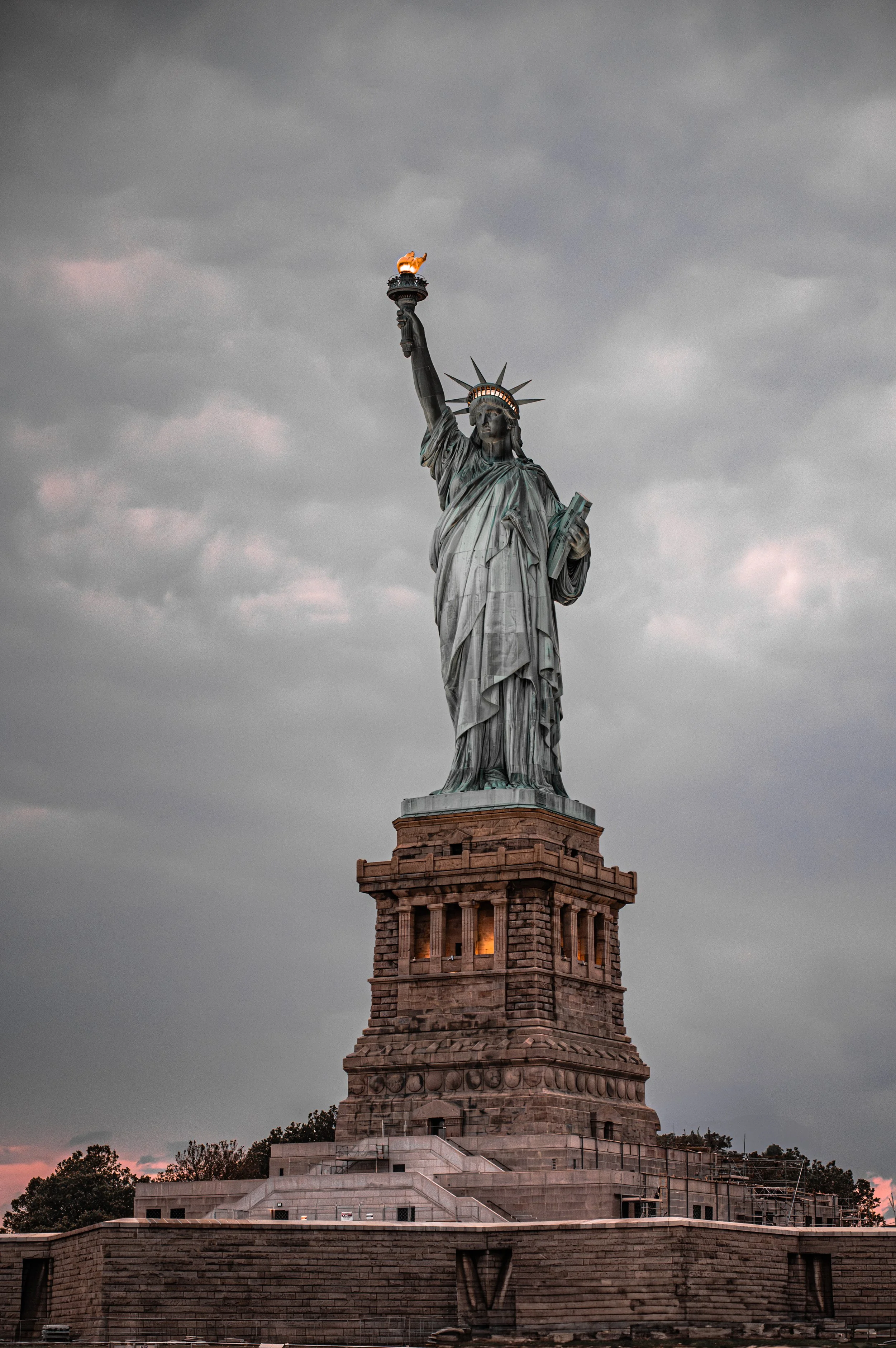 Statue of liberty standing tall with cloudy sky background.