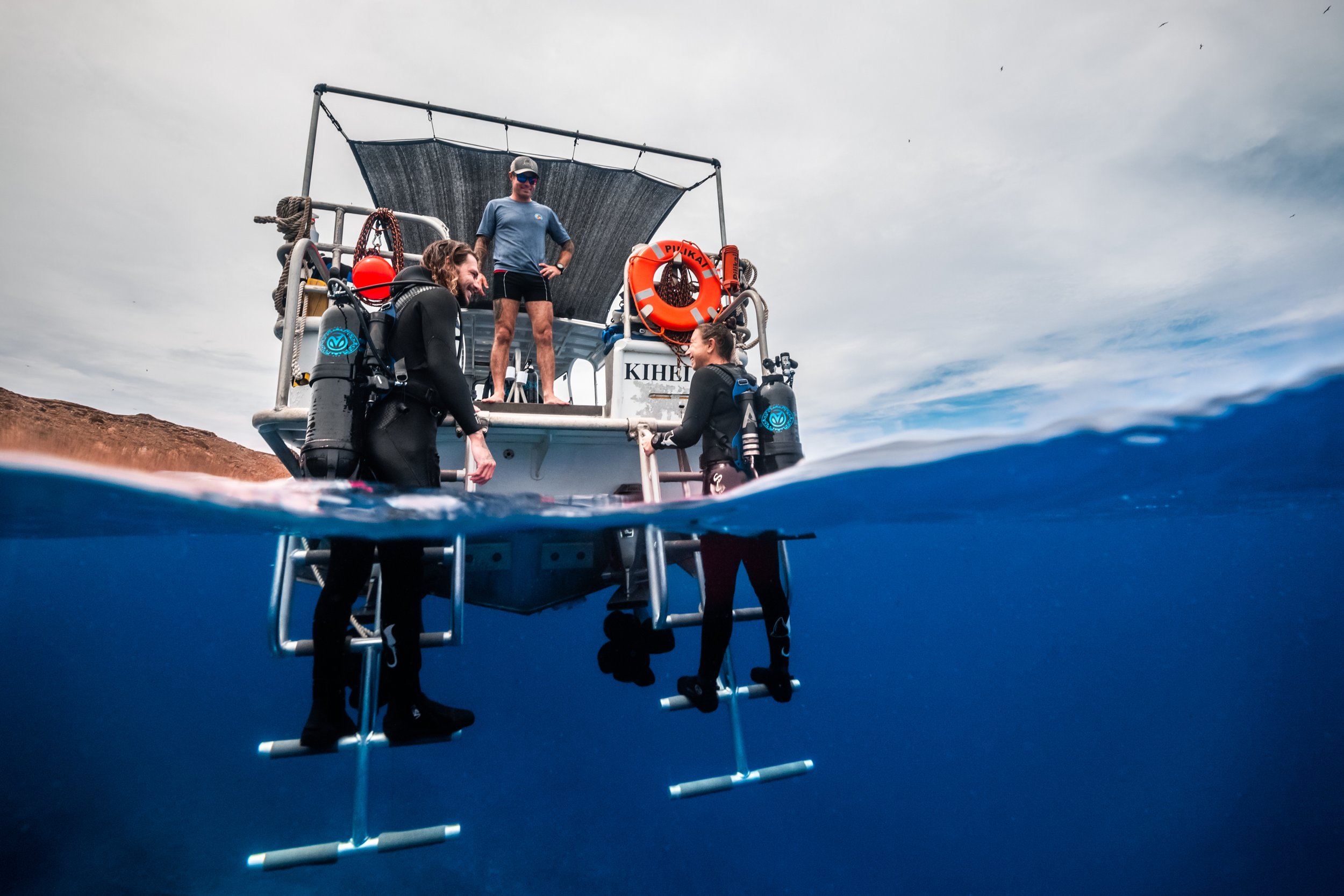 People preparing to scuba dive from a boat with diving gear, above and below water.