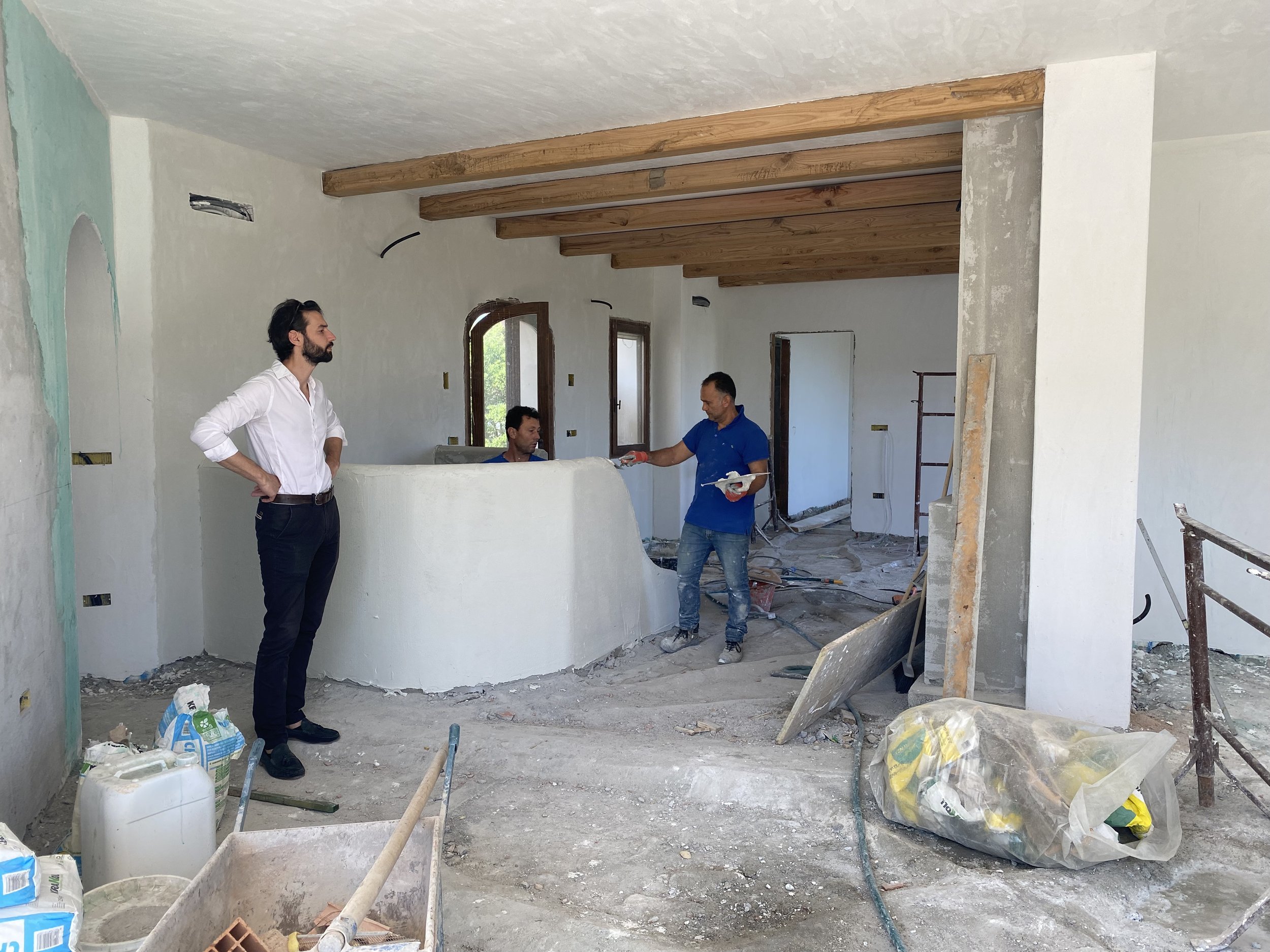Three men working on renovation inside a house under construction, with construction materials and tools around.