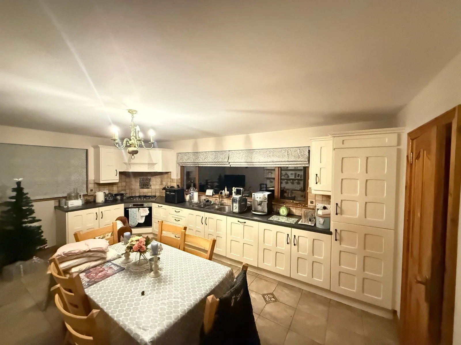 Kitchen and dining area with white cabinets, a wooden table with chairs, and a chandelier.