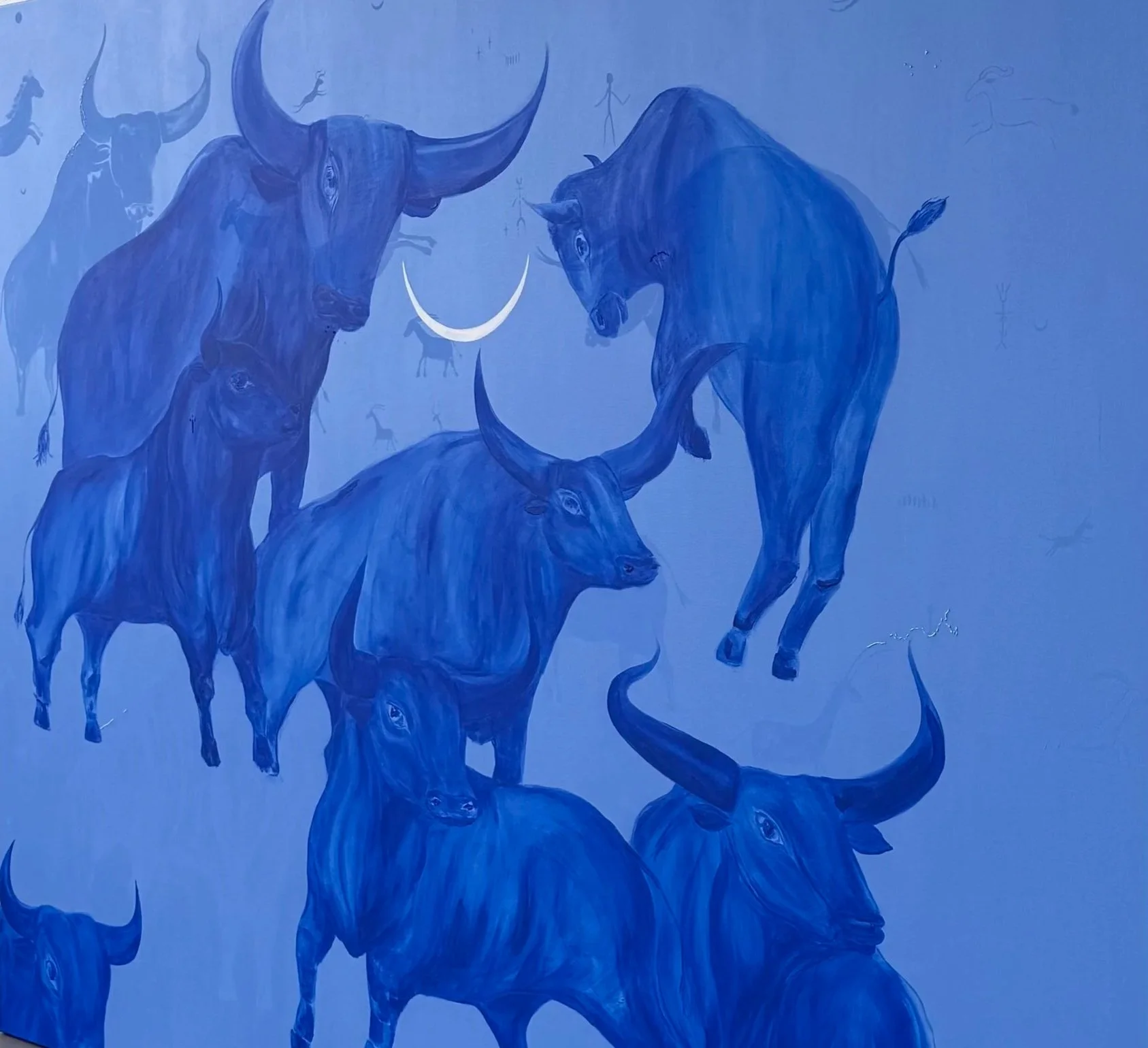 Still, We Return by Jevgenia Vassiljeva, 2026 — a large 200 × 160 cm blue acrylic painting featuring an overlapping herd of bulls, hidden animal figures, embroidered details and a white crescent moon.