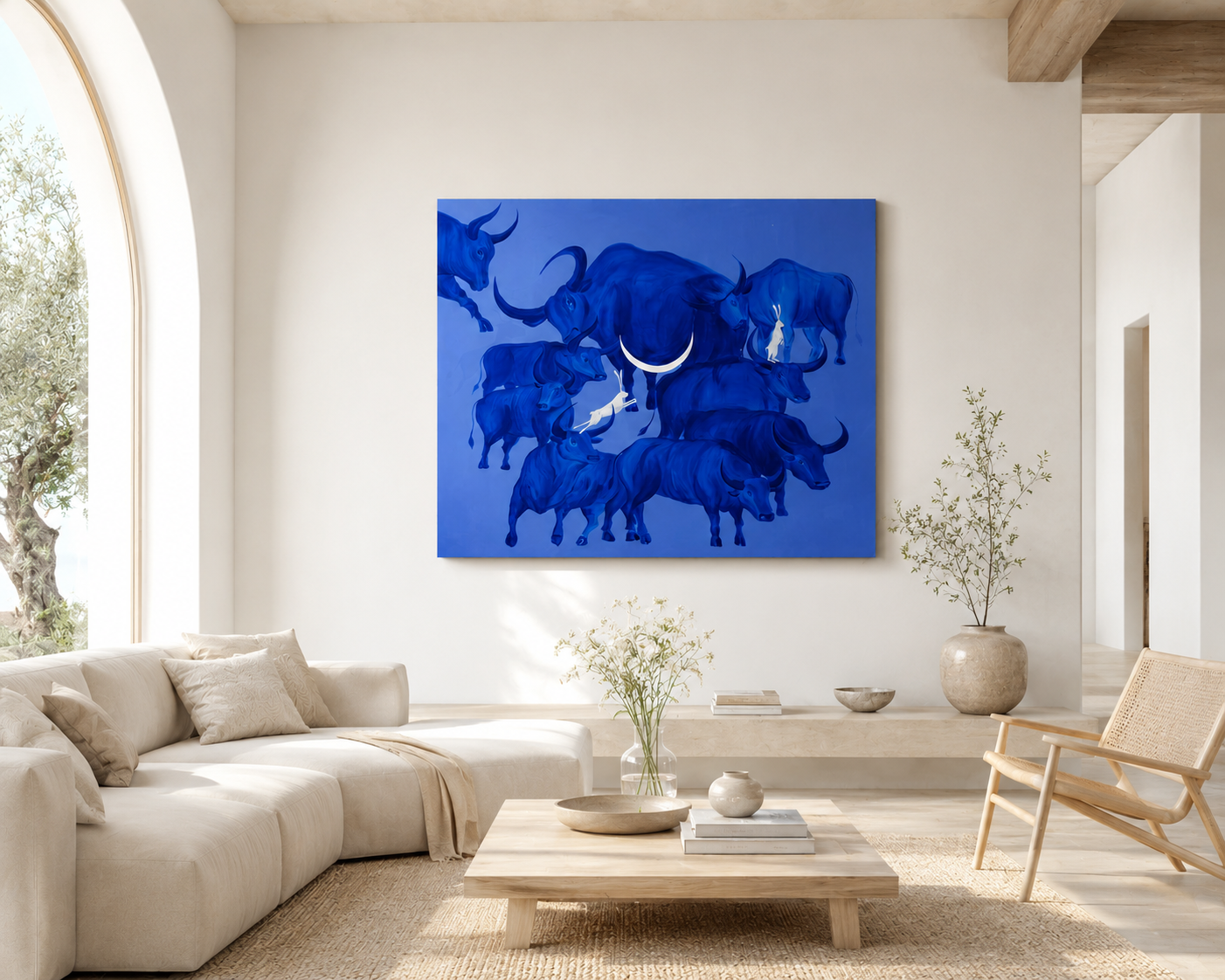 The Memory of the Herd painting displayed in a modern living room — large blue acrylic canvas with bulls and hares above a sofa, interior scale reference