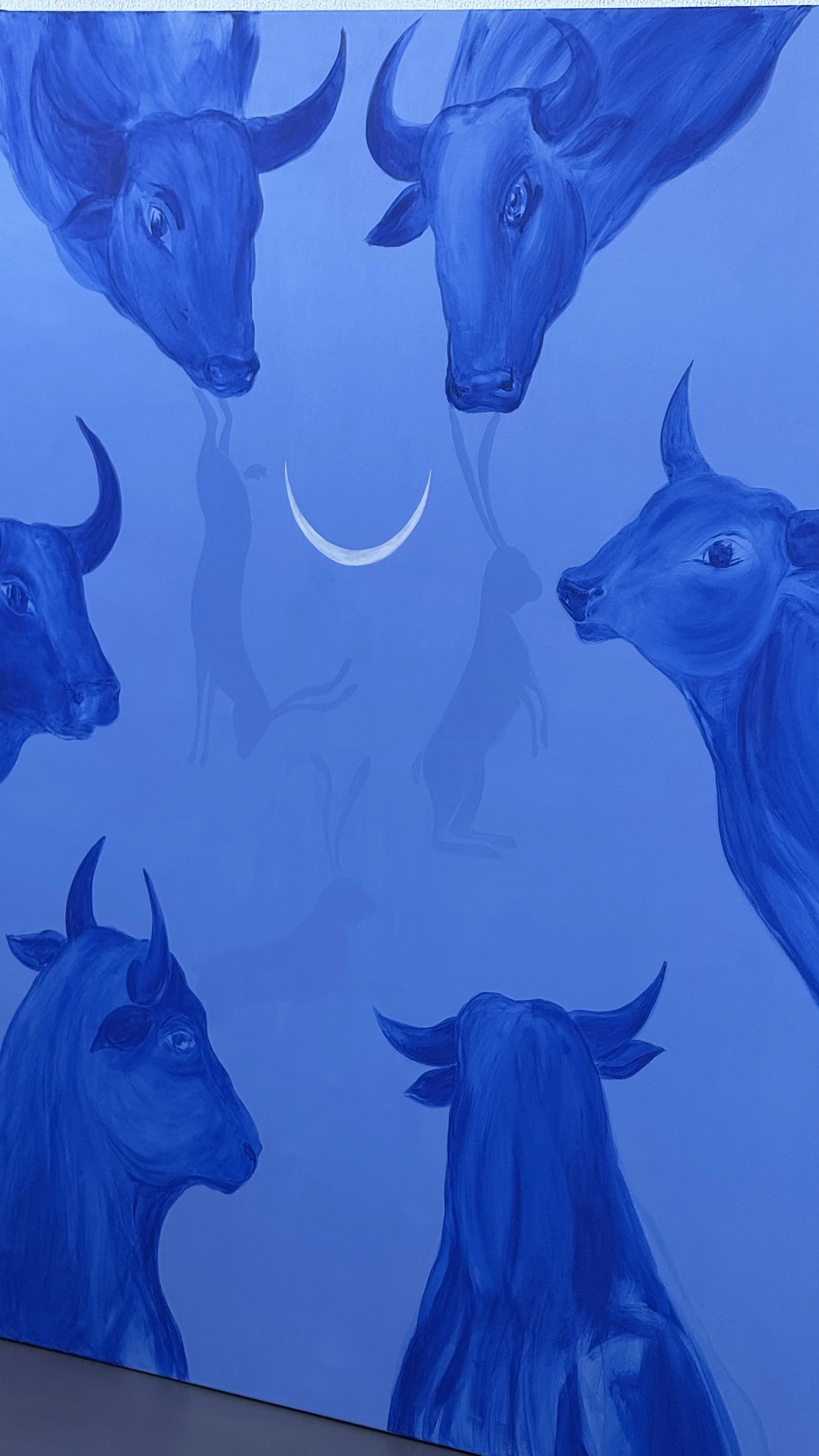 The Circle, a 150 × 150 cm blue acrylic painting by Jevgenia Vassiljeva featuring six bulls arranged around a crescent moon with hidden figures visible from different angles.