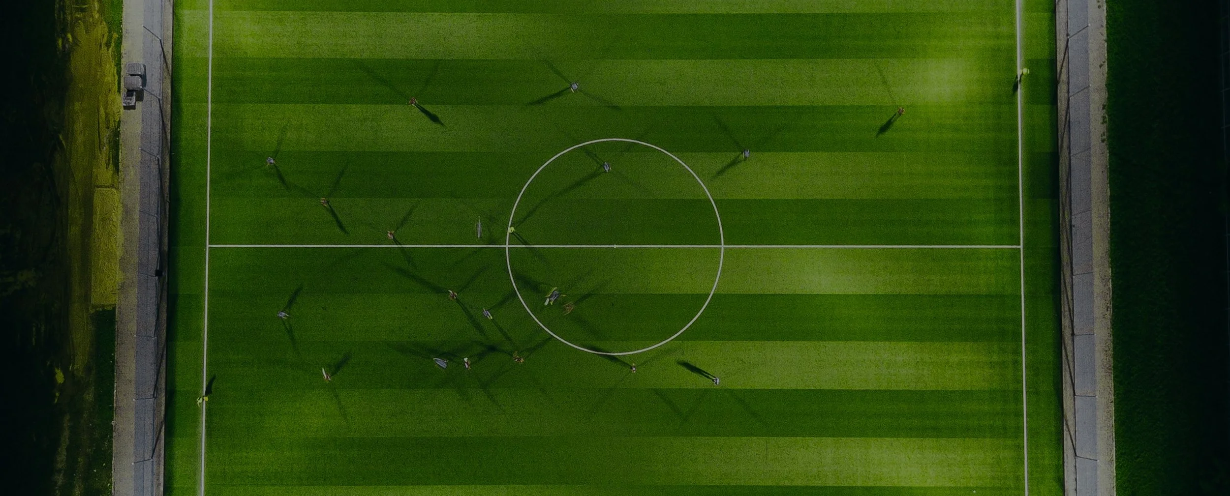Aerial view of a soccer field with players and their shadows playing.