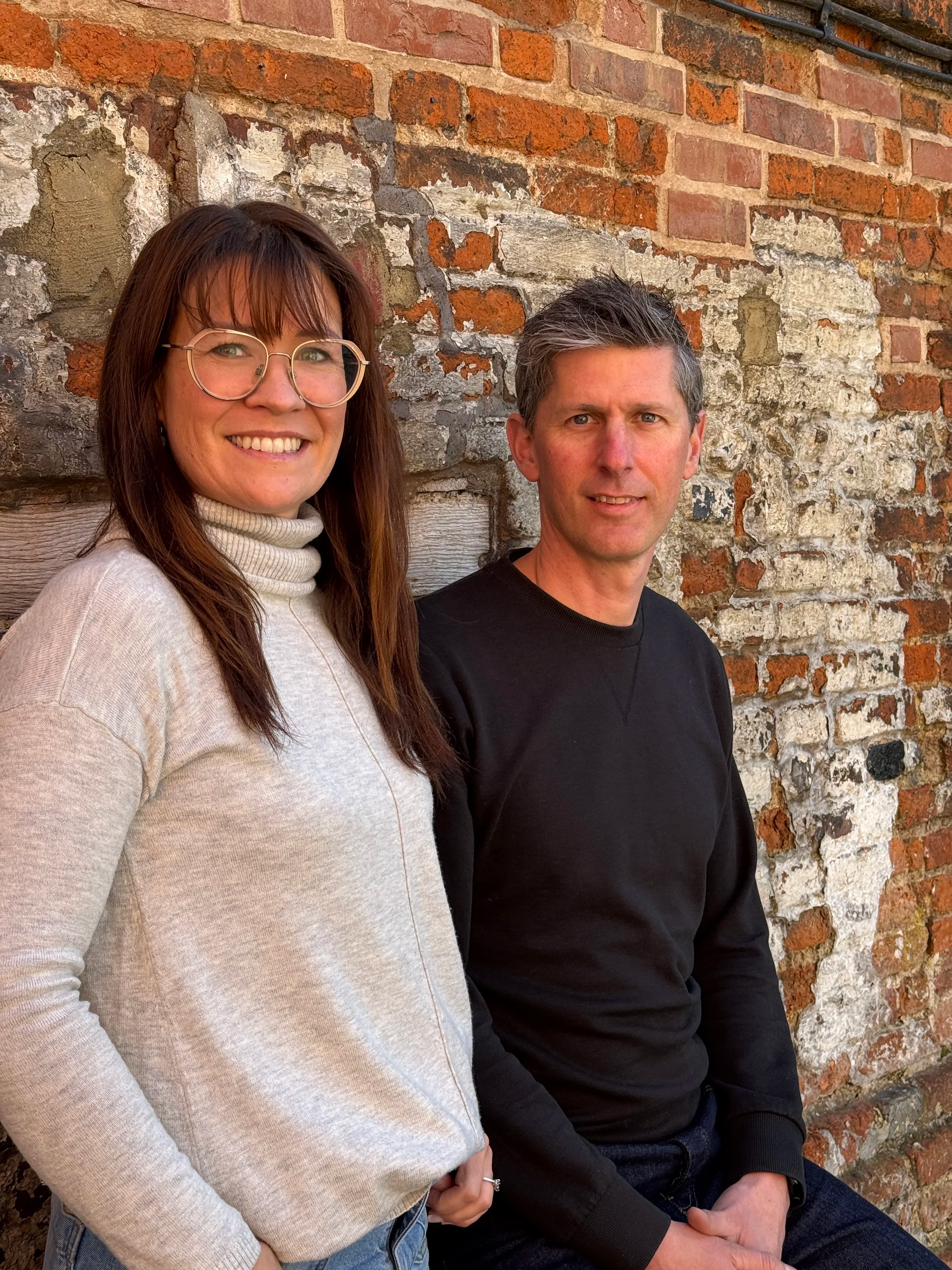Siri and Craig looking happy against a textured brick wall