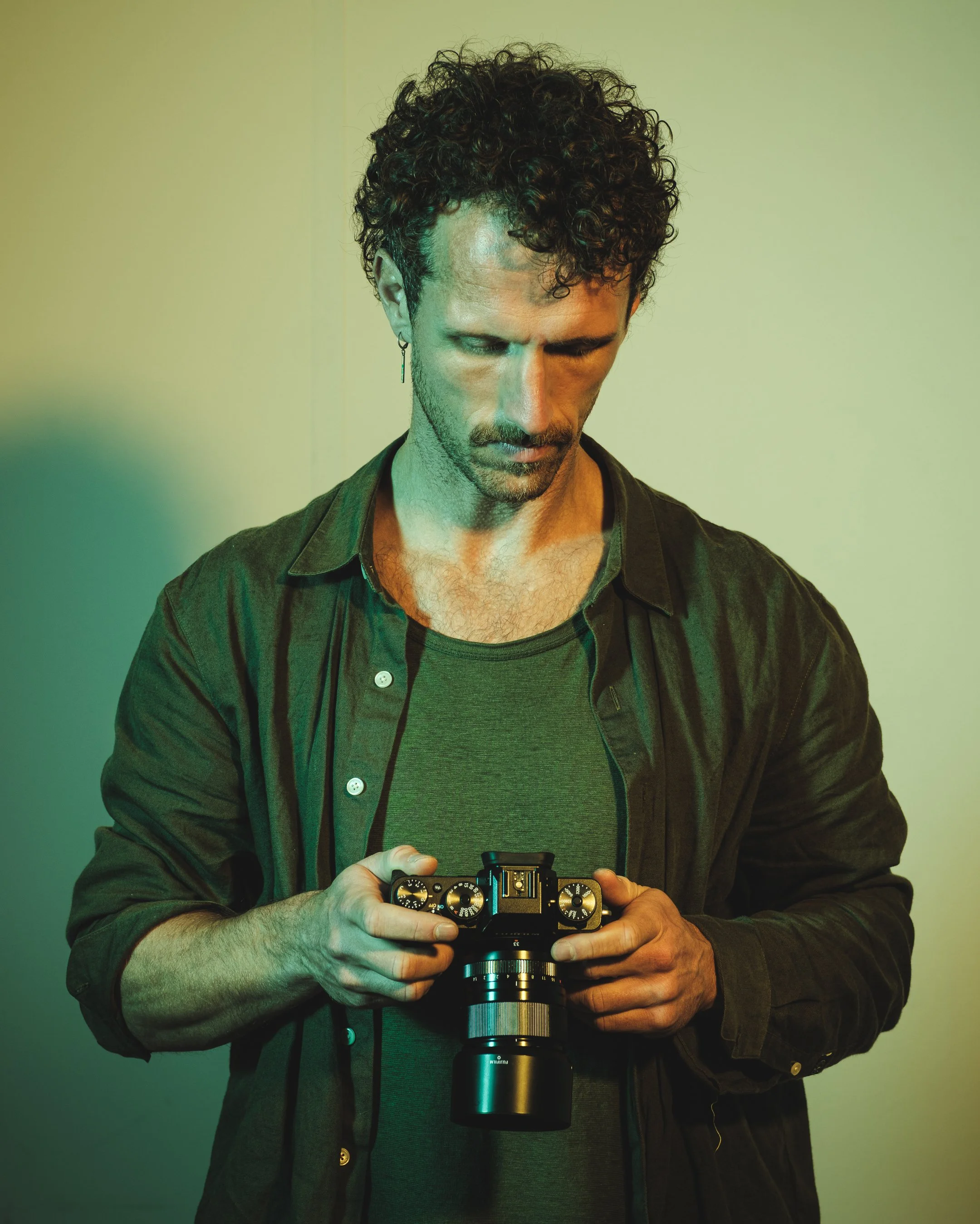 Man met gekruld haar bekijkt een camera en houdt deze vast.