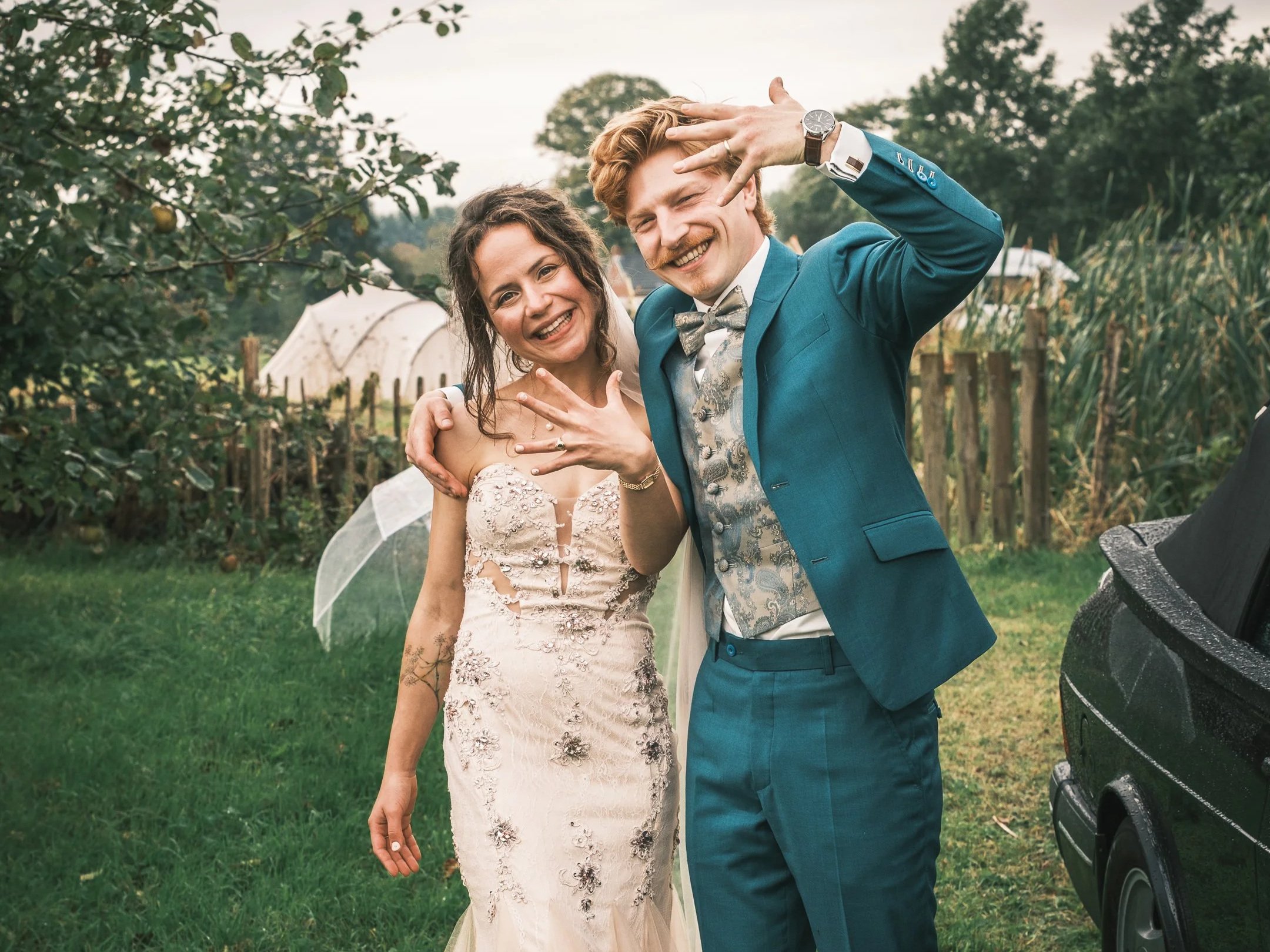 Mann und Frau bei einer Hochzeit, lachend und posierend draußen im Garten