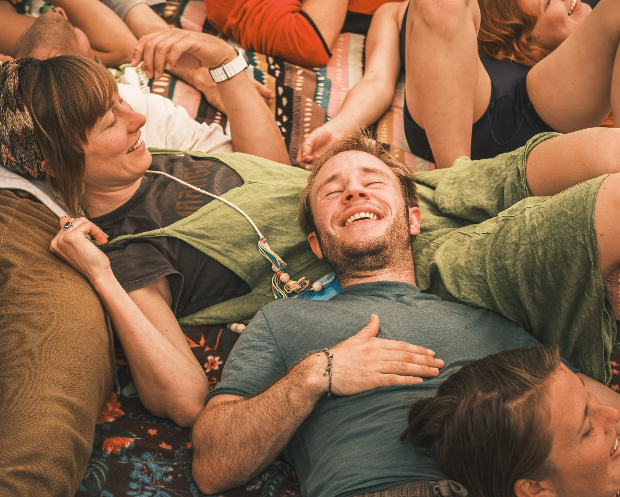 Mensen liggen op de grond en lachen, lijken te genieten van een ontspannen moment.