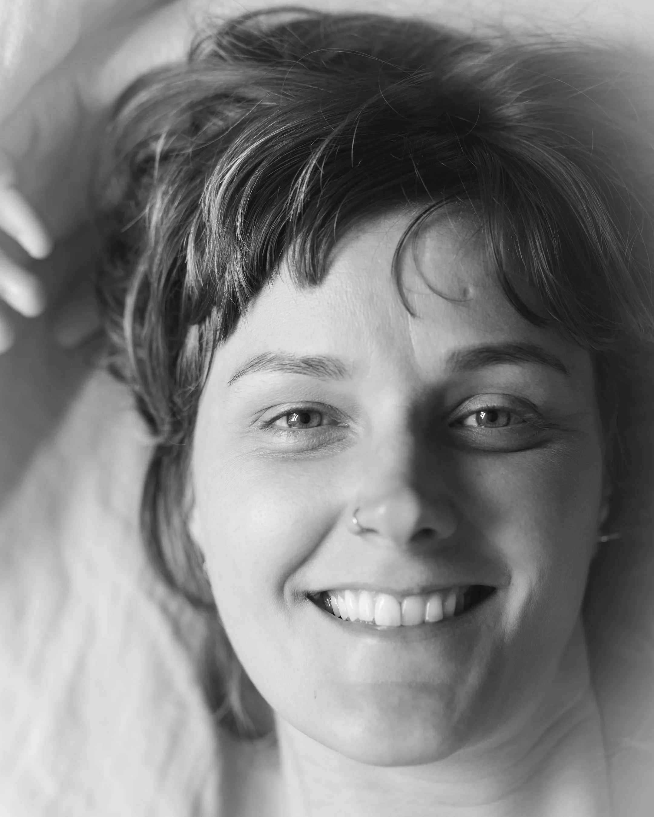 Kop van een lachende vrouw met kort, golvend haar en een nepneusje.