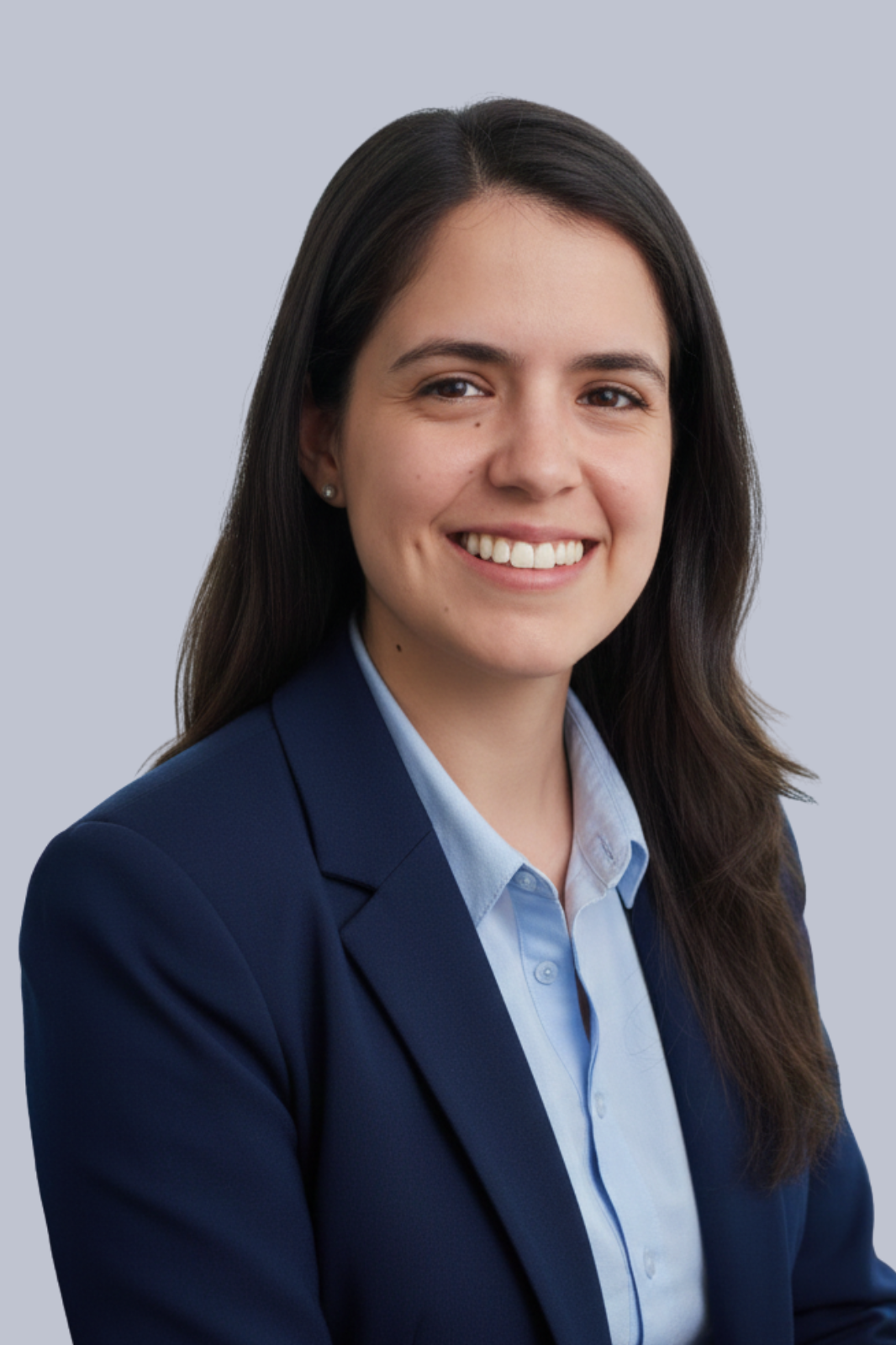 Retrato de una mujer joven con cabello largo y oscuro, vestida con blusa azul y saco azul, sonriendo frente a un fondo gris claro.
