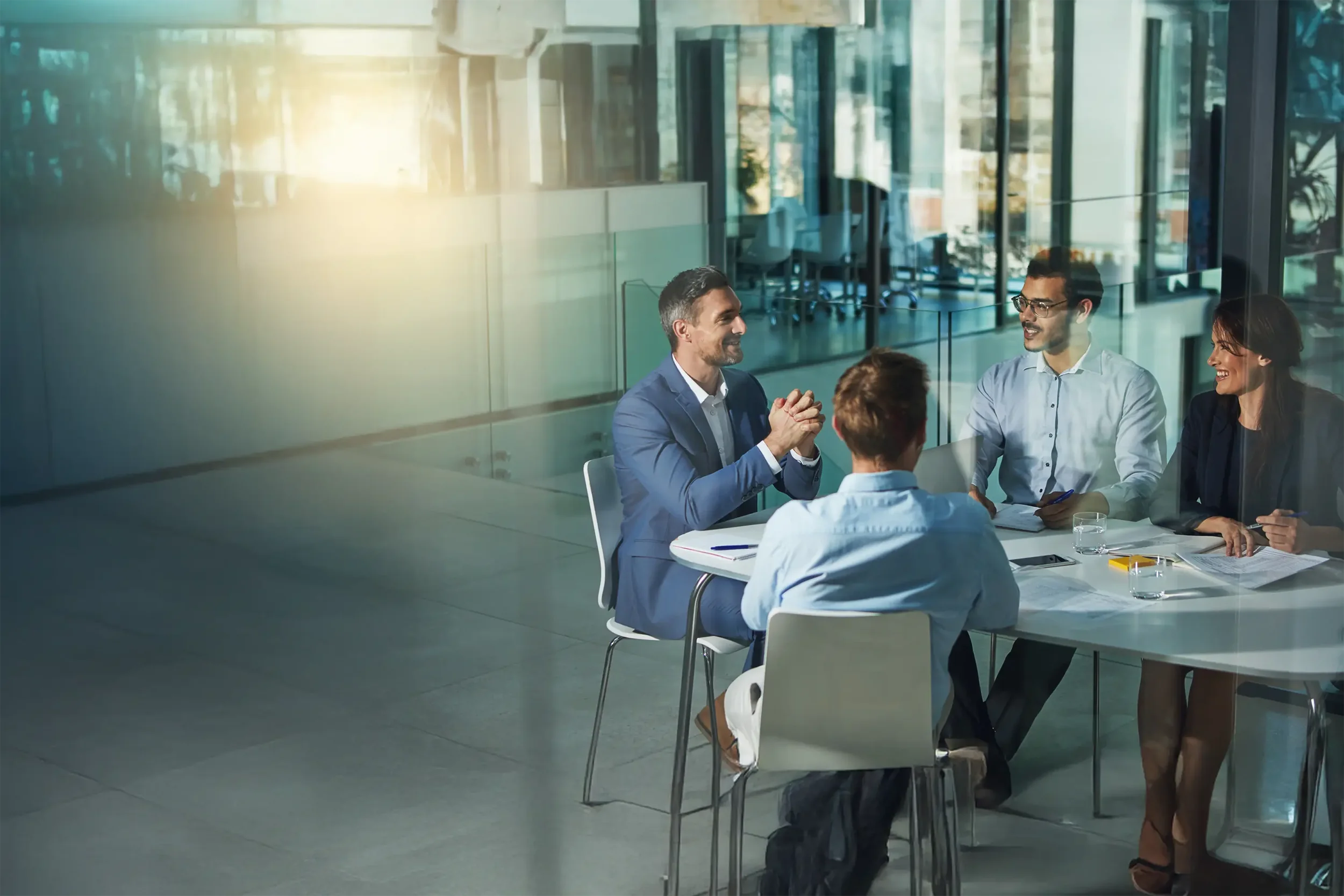 Four businesspeople sitting around a table in a modern office having a meeting.