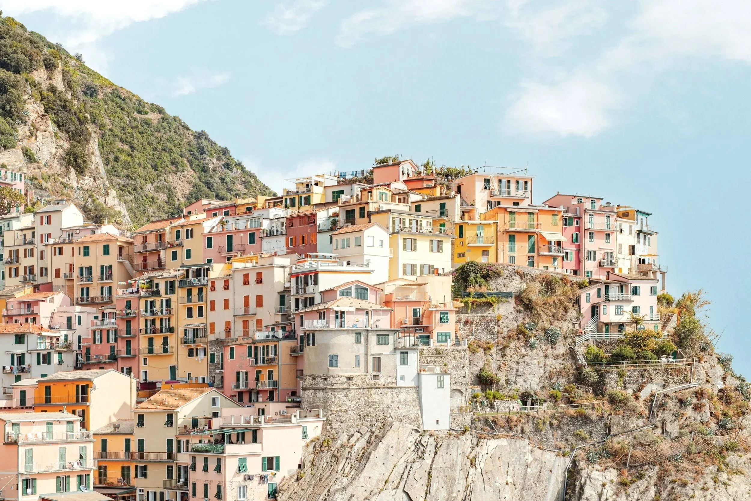 Colorful buildings clustered on a hillside with a mountain backdrop and a partly cloudy sky.