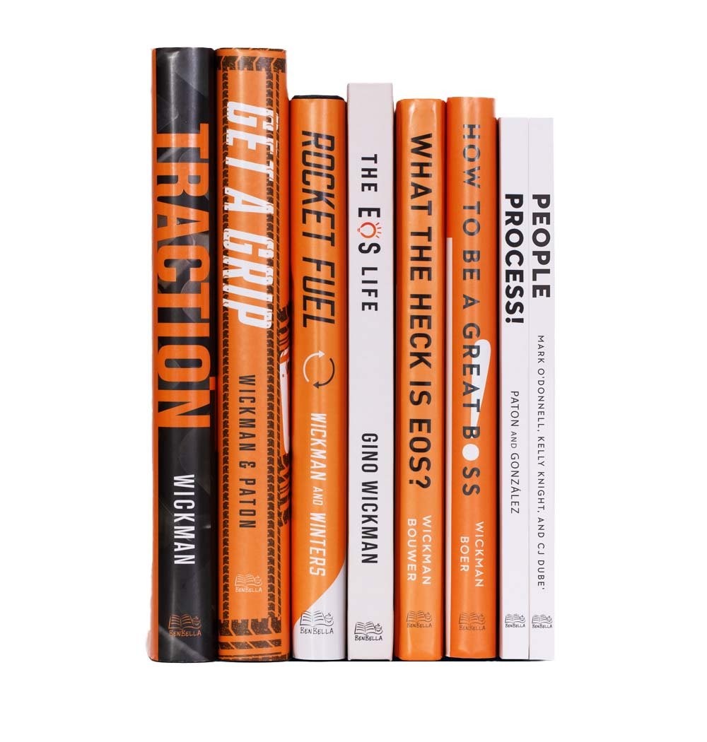 seven books on a white background with titles on the spines, including 'TRACTION' by Wickman, 'The 4-Hour Workweek' by Ferriss, 'The Rocket Fuel' by Wickman and Winters, 'The Ego's Life' by Gino Wickman, 'What the Hack is EOS?' by Wickman, 'How to Be a Great Boss' by Wickman, and 'People Process' by Mark Odonnell and Kelly Knight.