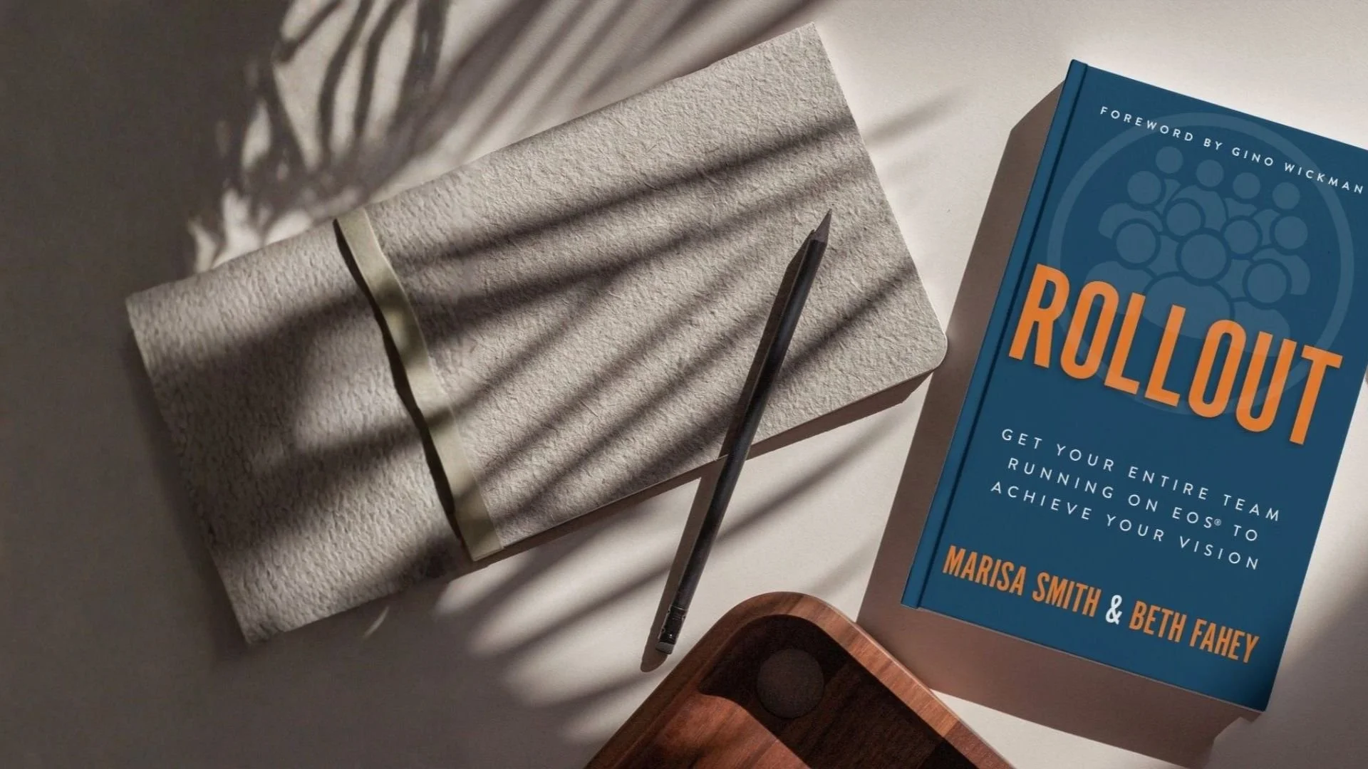 A blue hardcover book titled "Rollout" by Marisa Smith and Beth Fahey written to help leaders rollout eos to their entire companies.