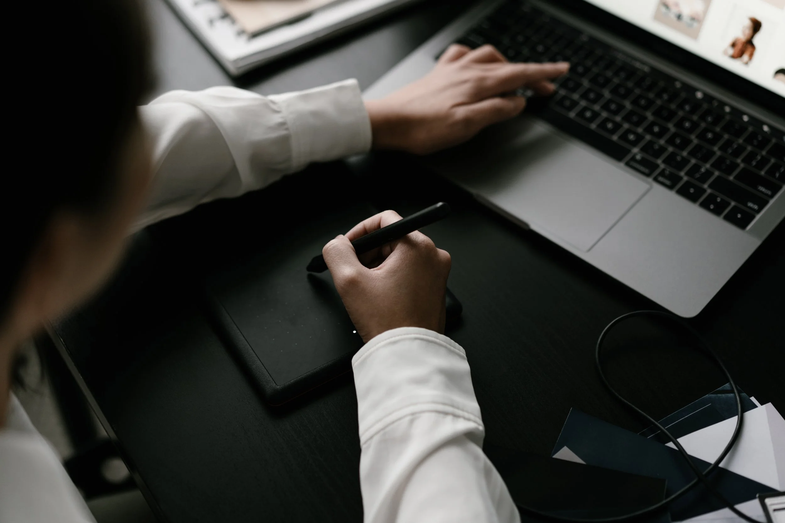Person using a graphics tablet, working on a laptop and digital art or design.