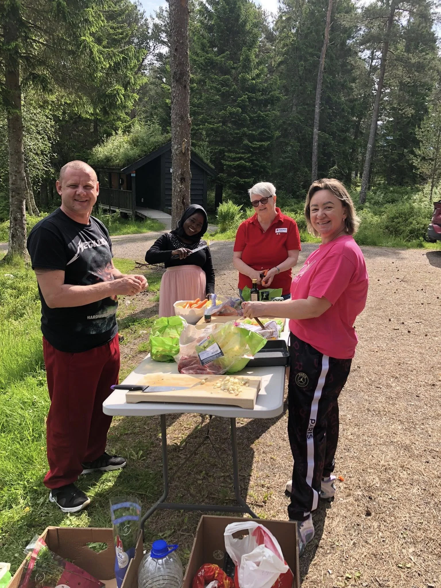 To personer står rundt et bord med mat, på en veg i et skogsområde