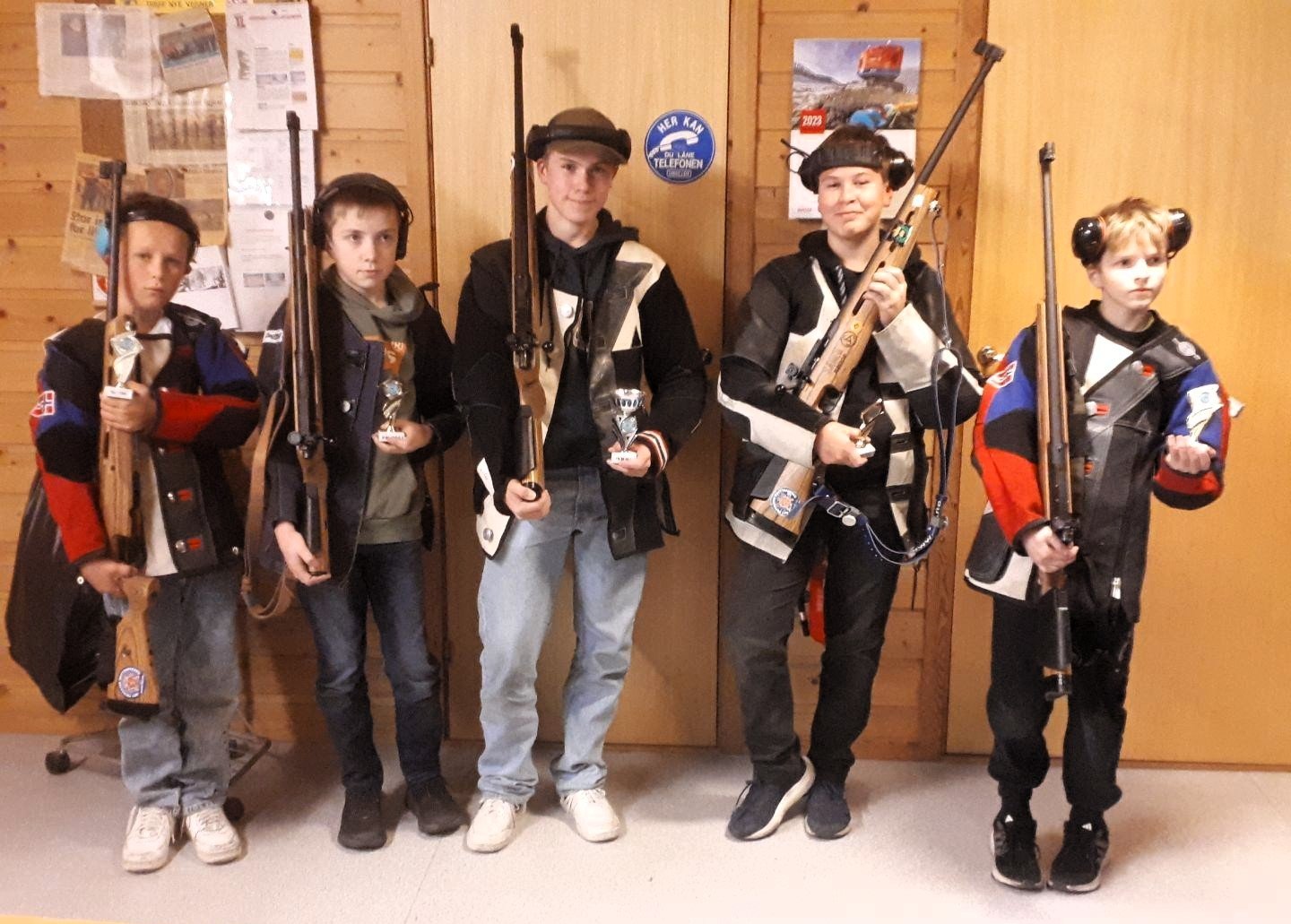 Ei gruppe yngre skyttarar med alt utstyr, våpen, jakker og hørselsvern