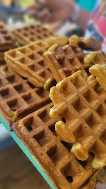Close-up of several chocolate waffles topped with sliced almonds on a tray