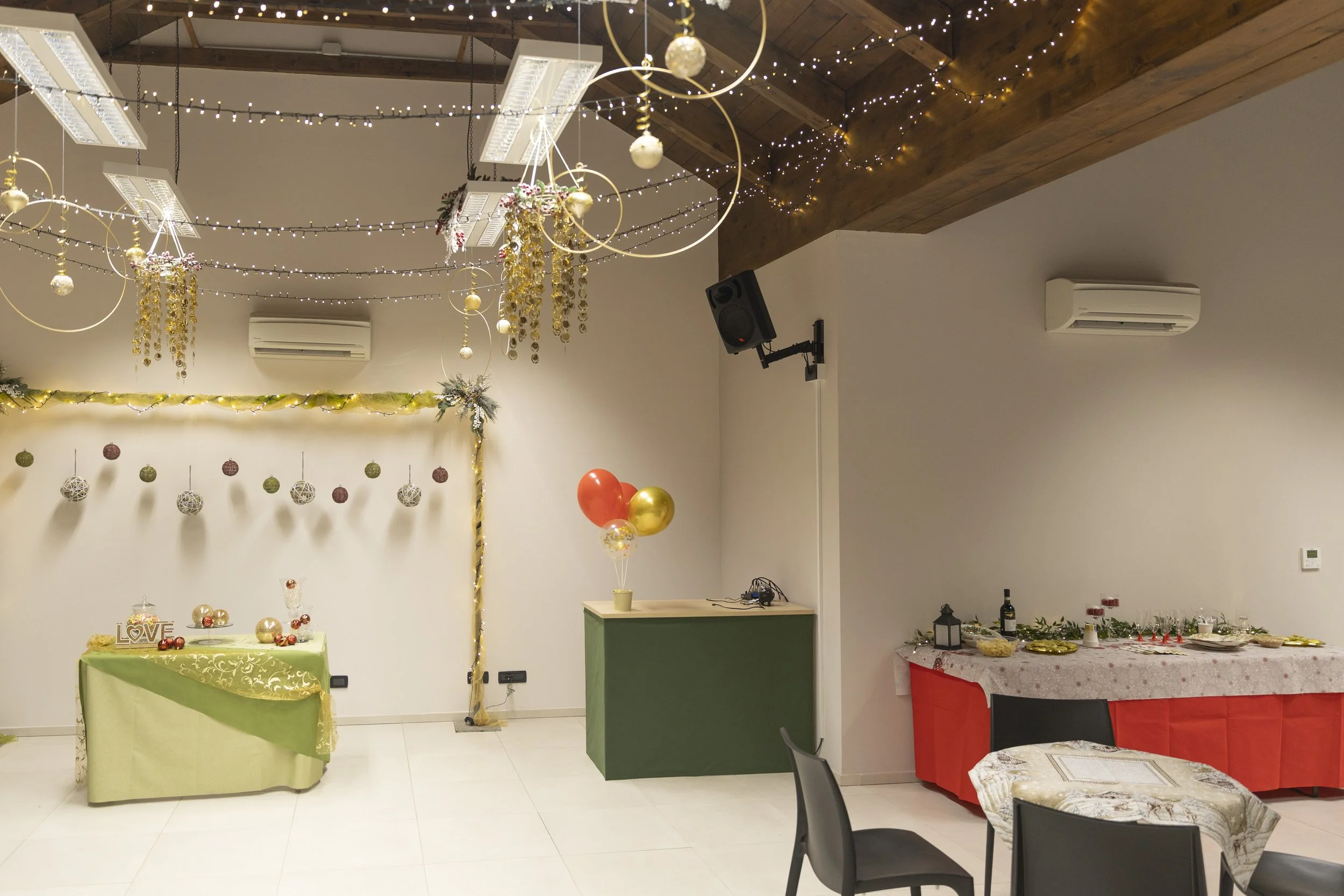 Decorazioni natalizie con luci, palline e nastri, in una stanza per festeggiamenti con tavolo di cibo e balloon rosso e oro.