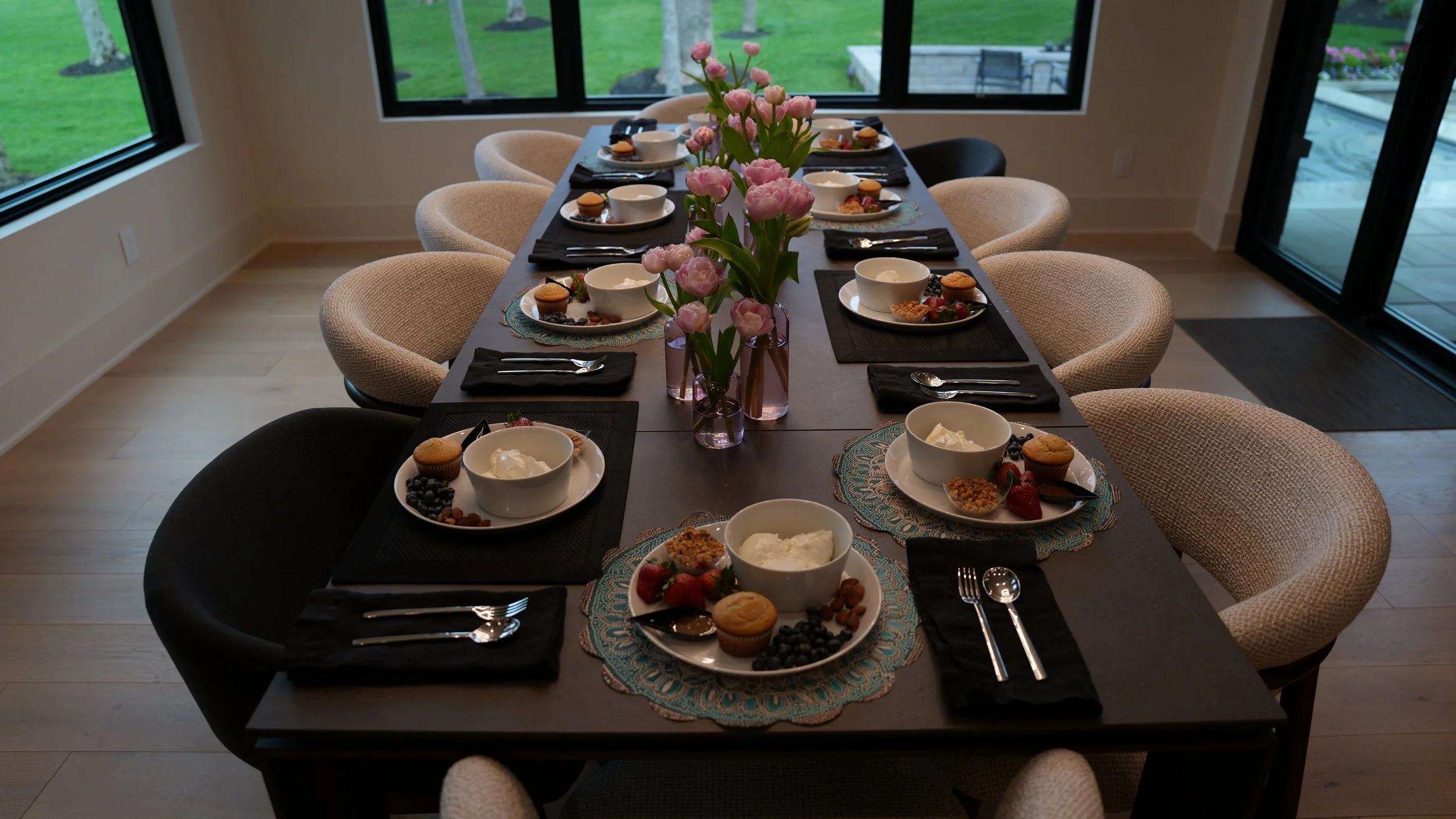 Breakfast table set with individual place settings, fruit, muffins, and pink tulips at the She Thinks Big retreat.