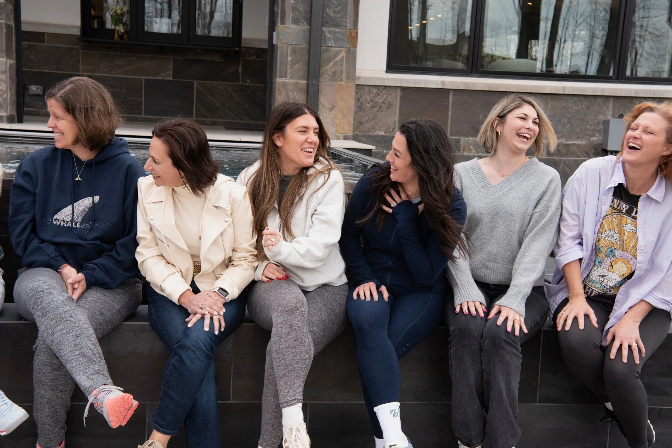 Women sitting together outdoors, laughing and talking during the She Thinks Big retreat.