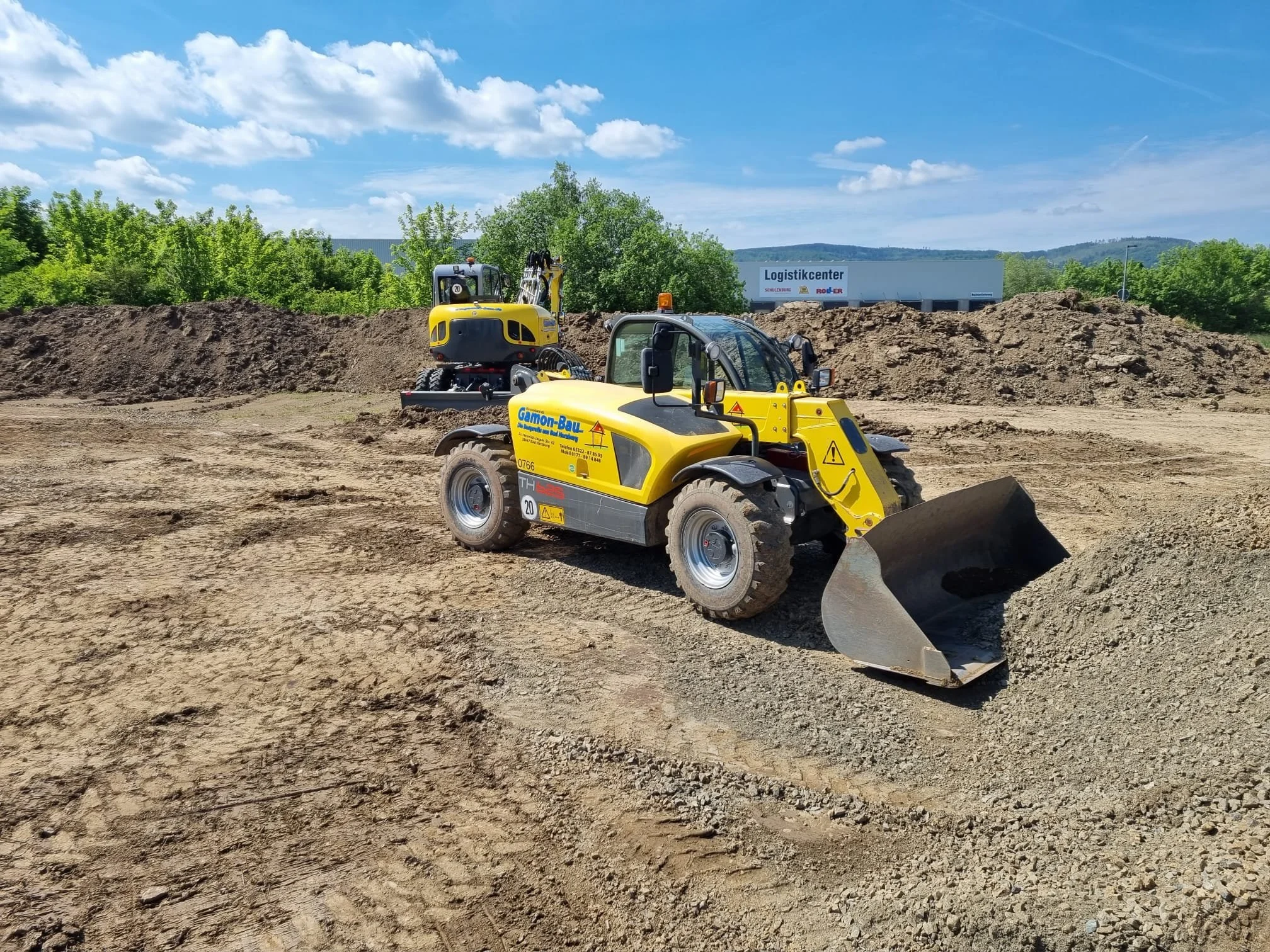 Baugeräte Teleskoplader bei Bauarbeiten auf einer Baustelle im Freien, mit einem gelben Frontlader und einem Minibagger im Hintergrund.