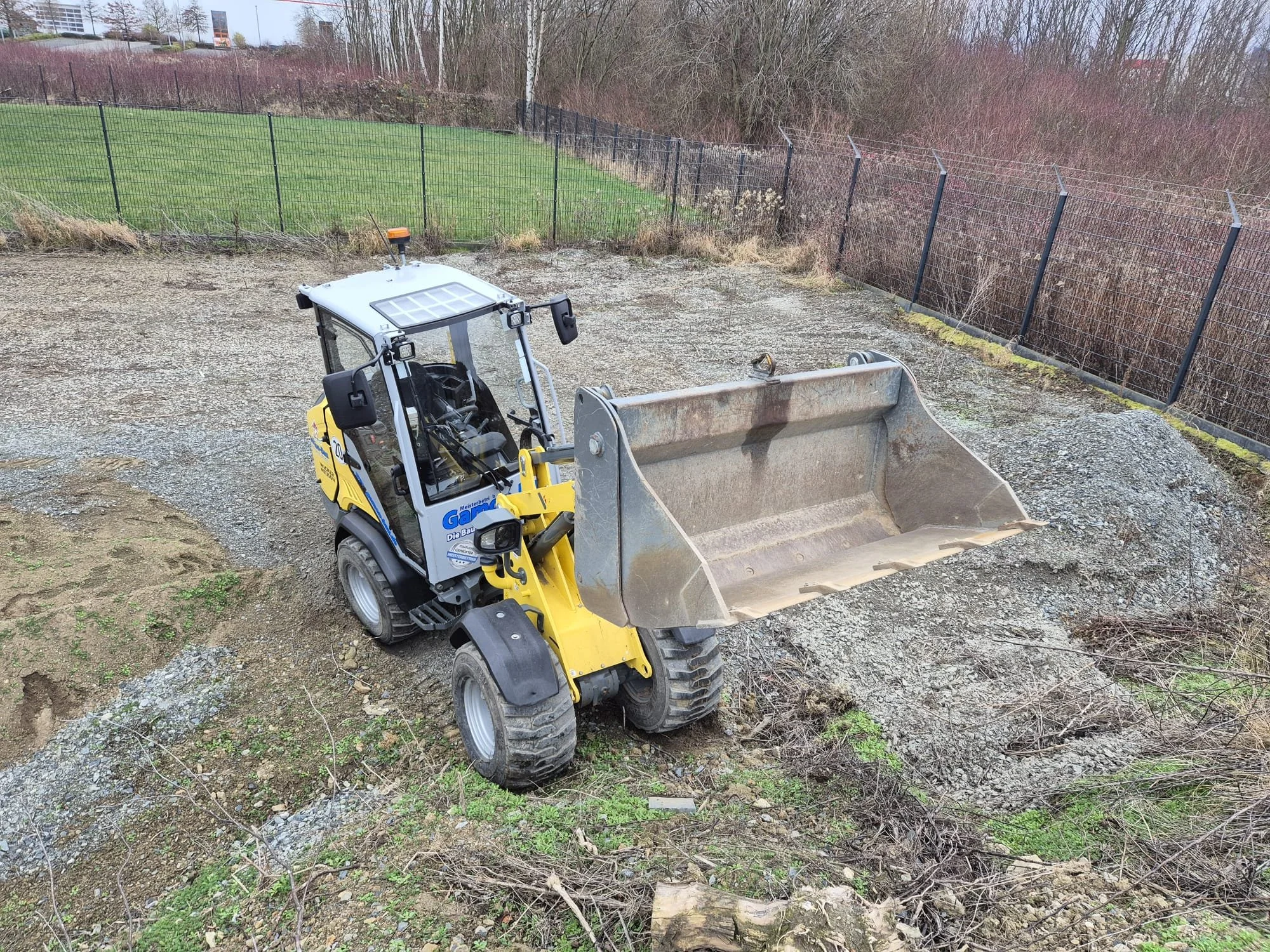 Ein gelber Radlader auf einer Baustelle, der Erde bewegt.