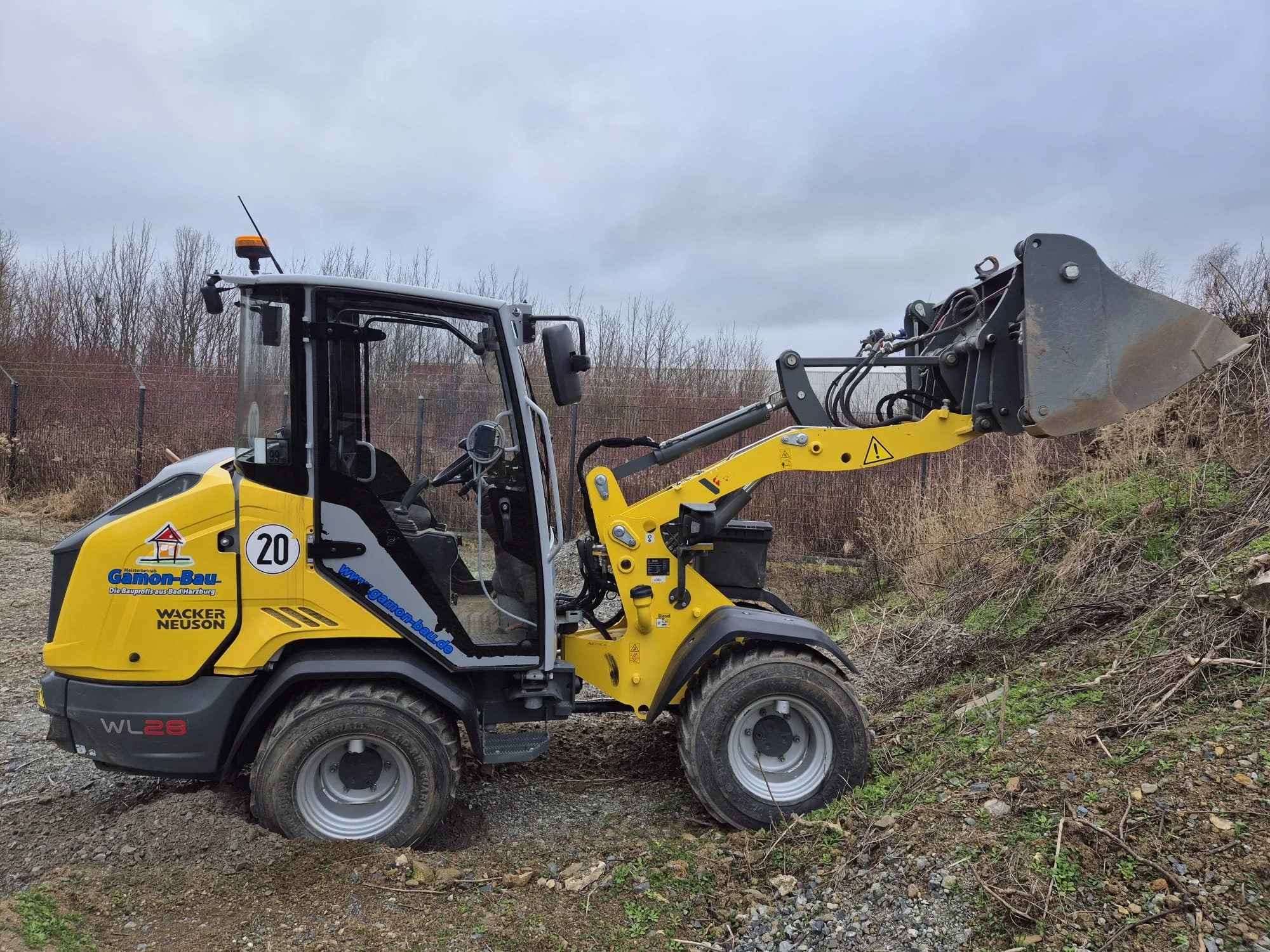 Radlader beim Greifen von Erdreich an einem Hügel.