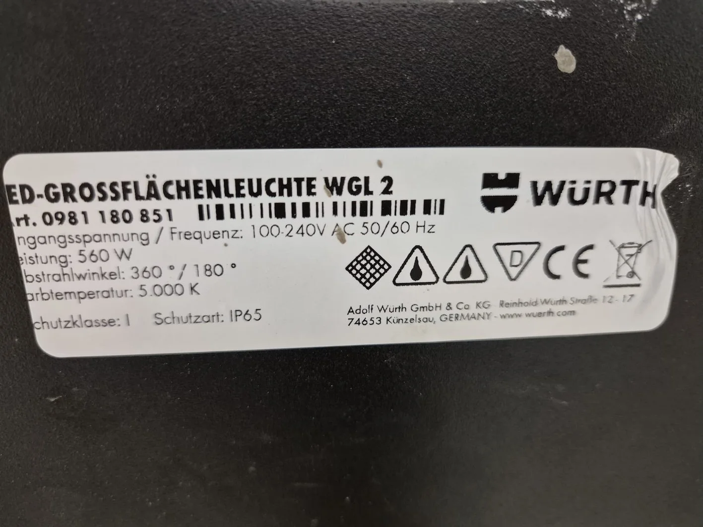 Aufkleber auf einem schwarzen Gerät mit weißen Etiketten, zeigt technische Spezifikationen für eine LED-Deckenleuchte, darunter Leistung, Spannung, Temperatur, und Gebrauchshinweise.