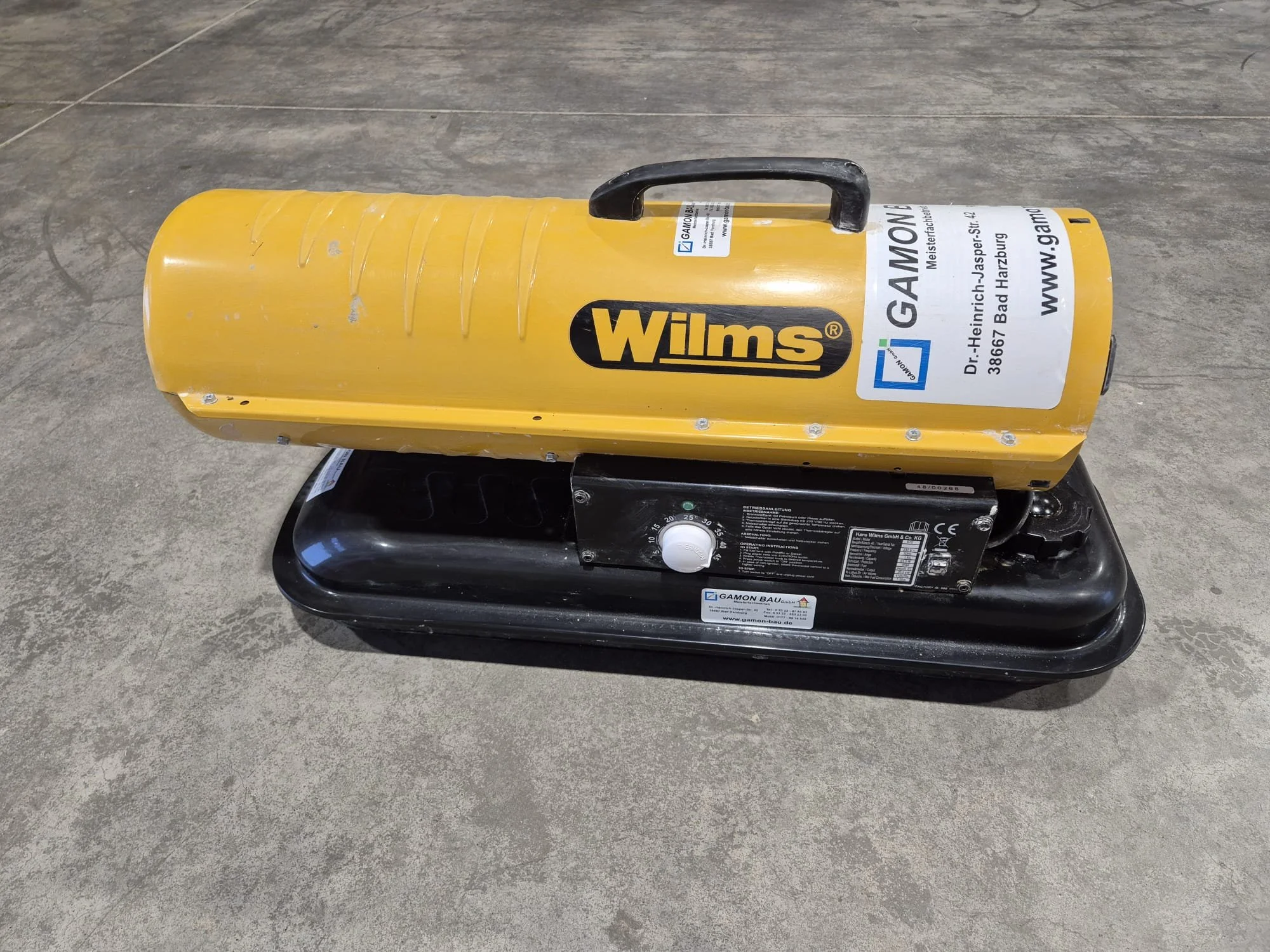 Mobiler Luftzerstäuber mit gelbem Gehäuse und schwarzem Stand, mit Aufklebern und Griff.