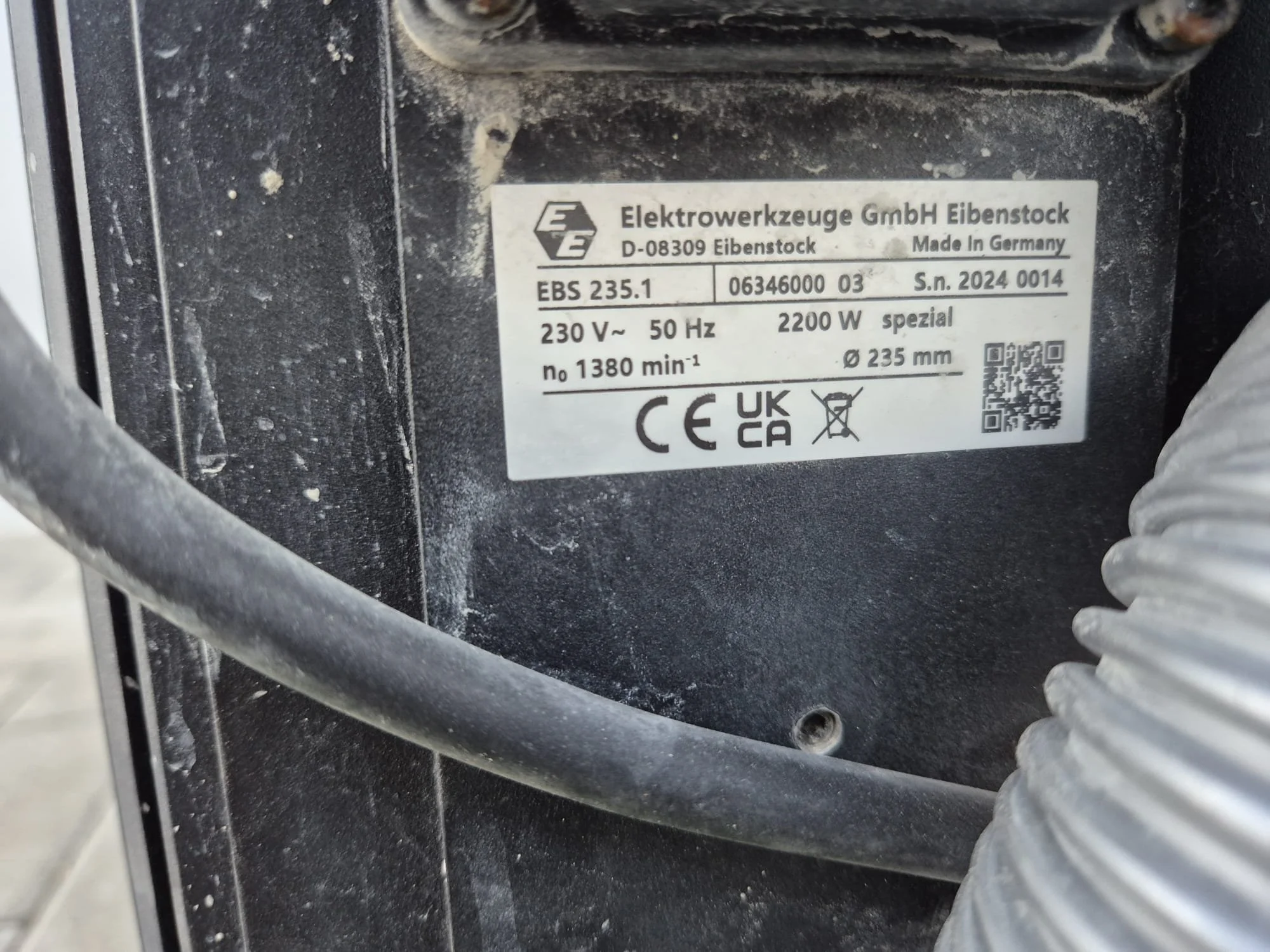 Aufkleber auf einer Maschine mit Informationen zum Hersteller, Modell, Spannung, Leistung und Zertifizierungen.