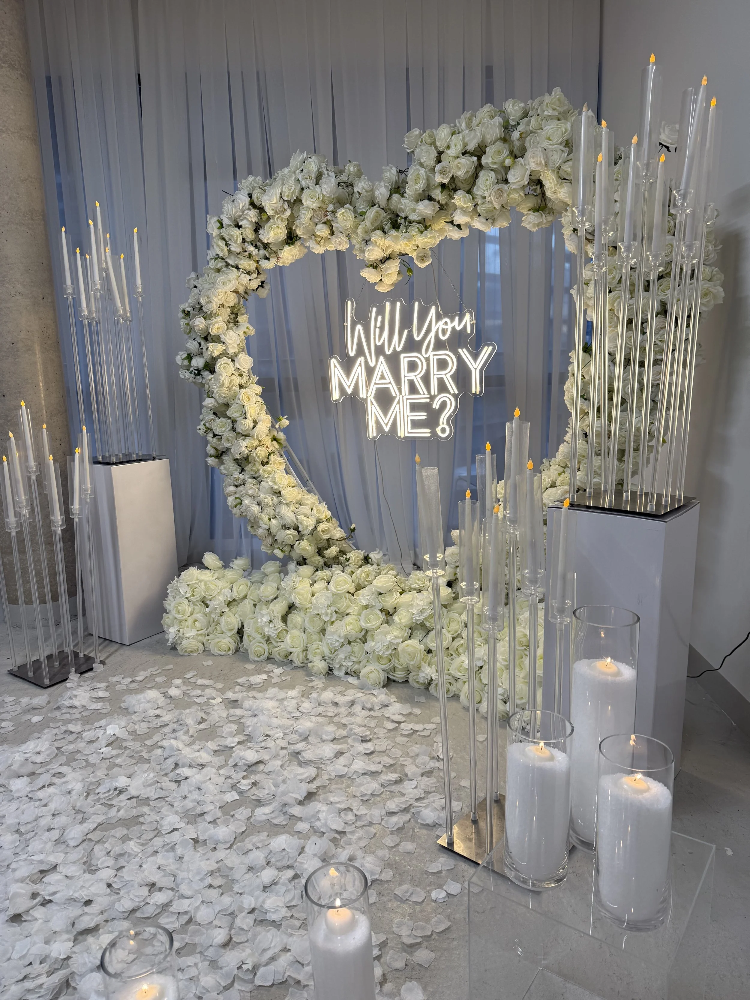 Black rotary telephone resting on a metallic wire side table next to a black leather chair in a room with a white wall and a patterned rug.