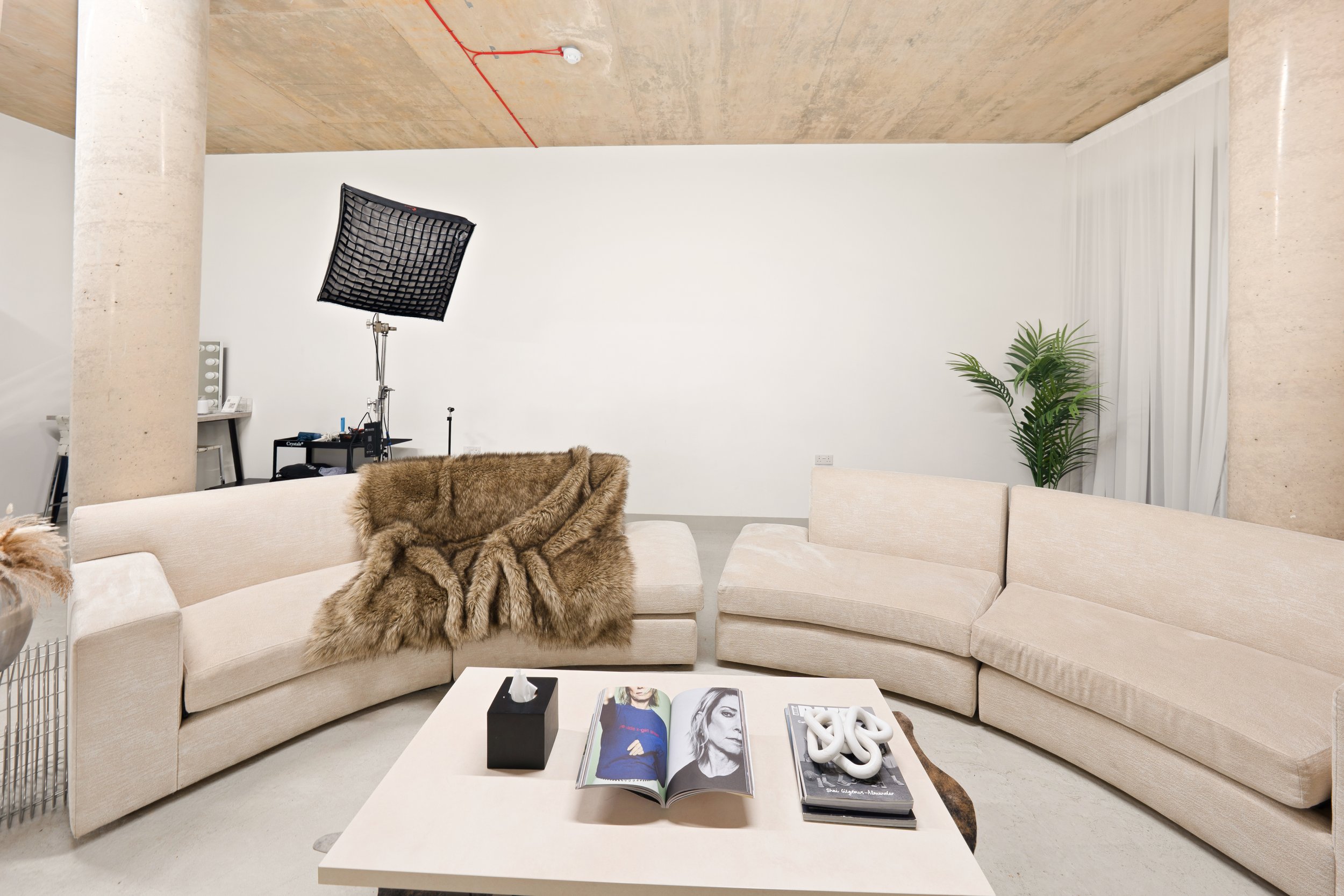 A modern lifestyle set at Urbn Link Studios in East London, featuring a stylish living room with a contemporary sofa, coffee table, textured décor, natural light, and professional photography equipment,ideal for branding shoots, lifestyle photography