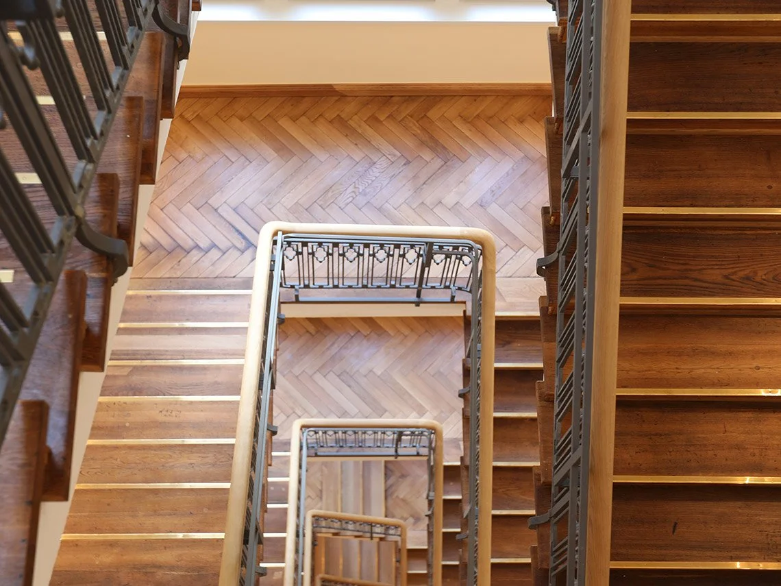 Blick nach oben auf eine hölzerne Treppe mit verzinktem Geländer, die nach unten führt.