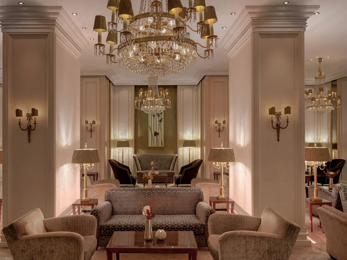 Luxuriöser Lounge-Bereich mit Sofas, Sesseln, Tisch, Stehlampen, Wandleuchtern und Kronleuchtern in eleganter Einrichtung.
