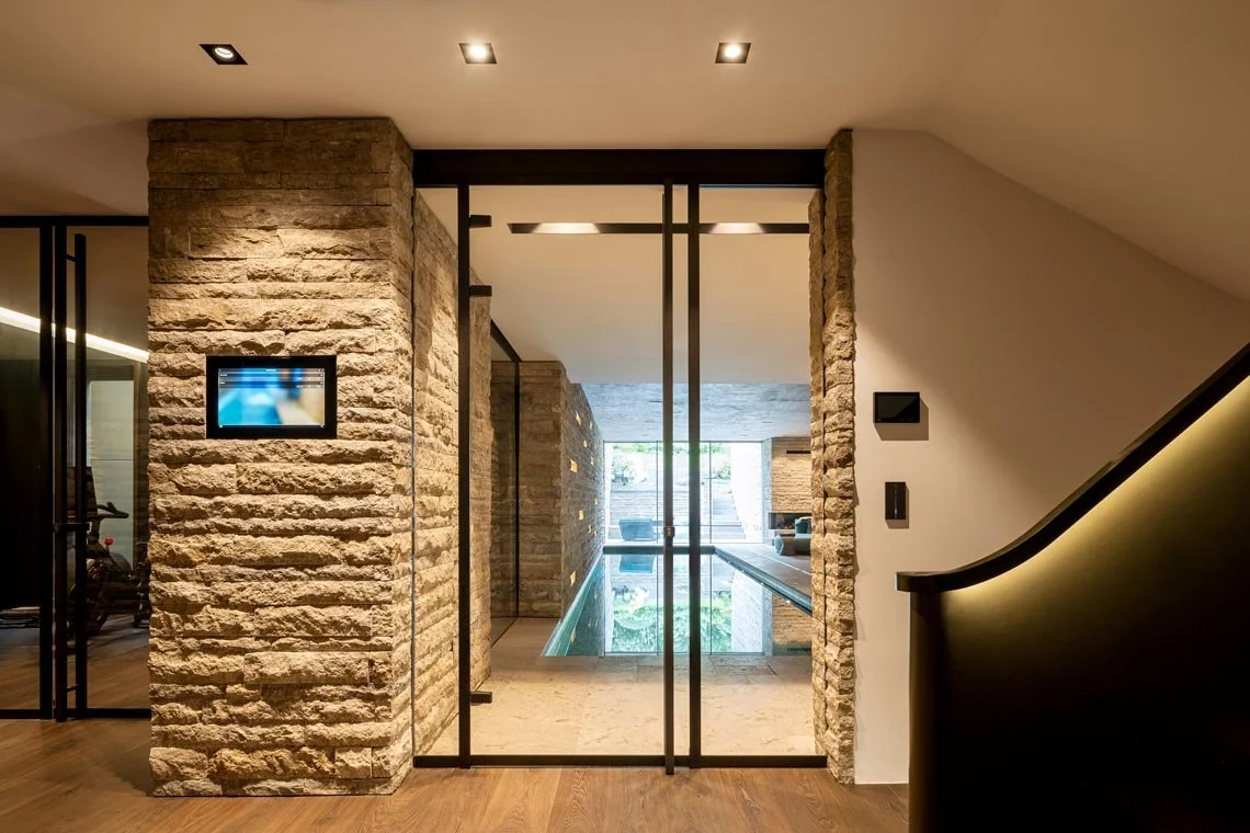 Moderner Eingangsbereich mit einer Glastür, Sandsteinwänden und einem Pool in einem Wohnhaus