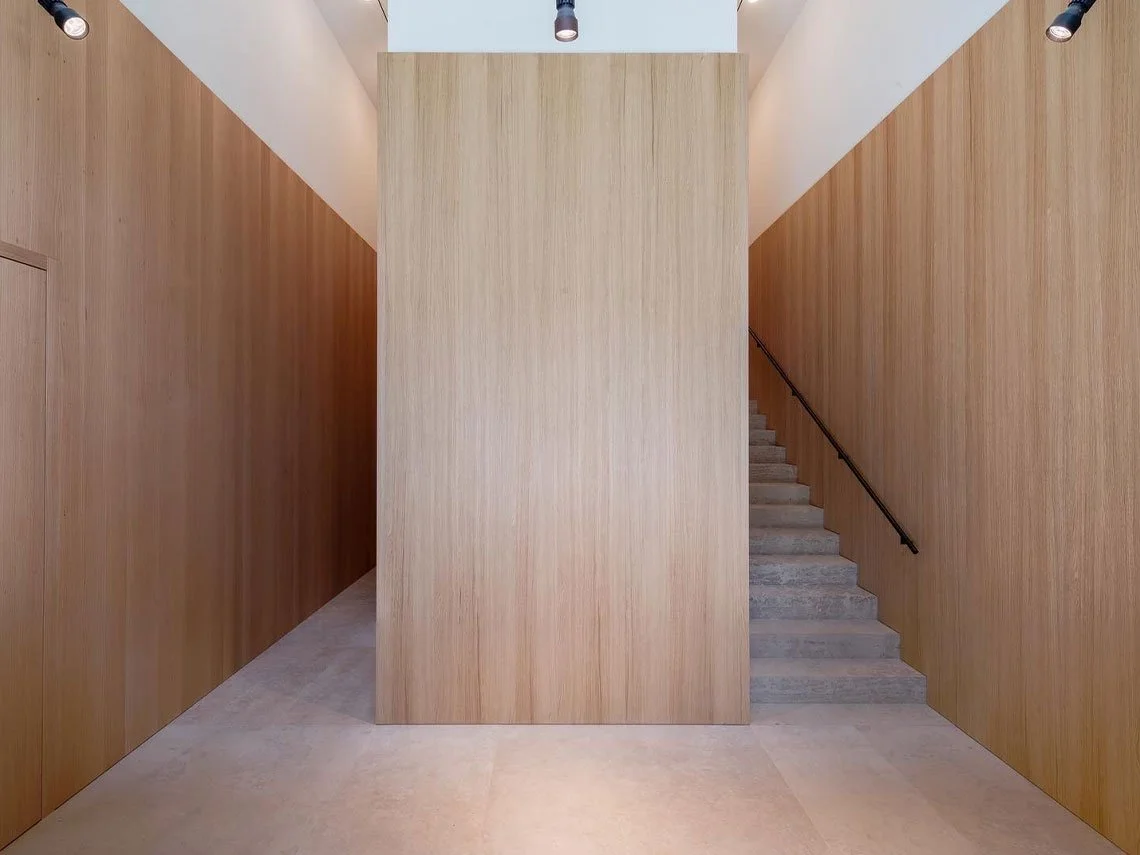 Innenraum mit Holzverkleidungen, Treppe auf der rechten Seite, zentral eine große Holztafel.