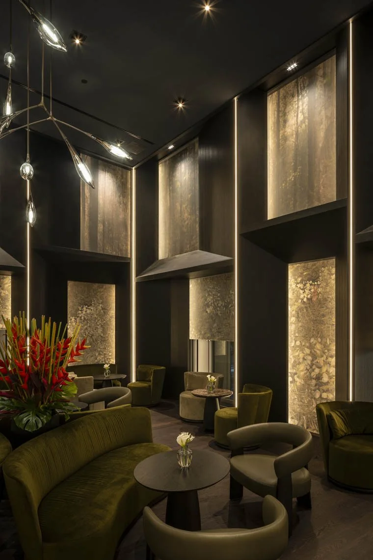 Eleganter Lounge-Bereich mit modernen dunklen Wänden, leuchtenden vertikalen Linien, gepolsterten Stühlen und Tischen, dekorativen Blumenvasen, mit weichem Licht und Sicht auf eine Baumwand durch die Fenster.