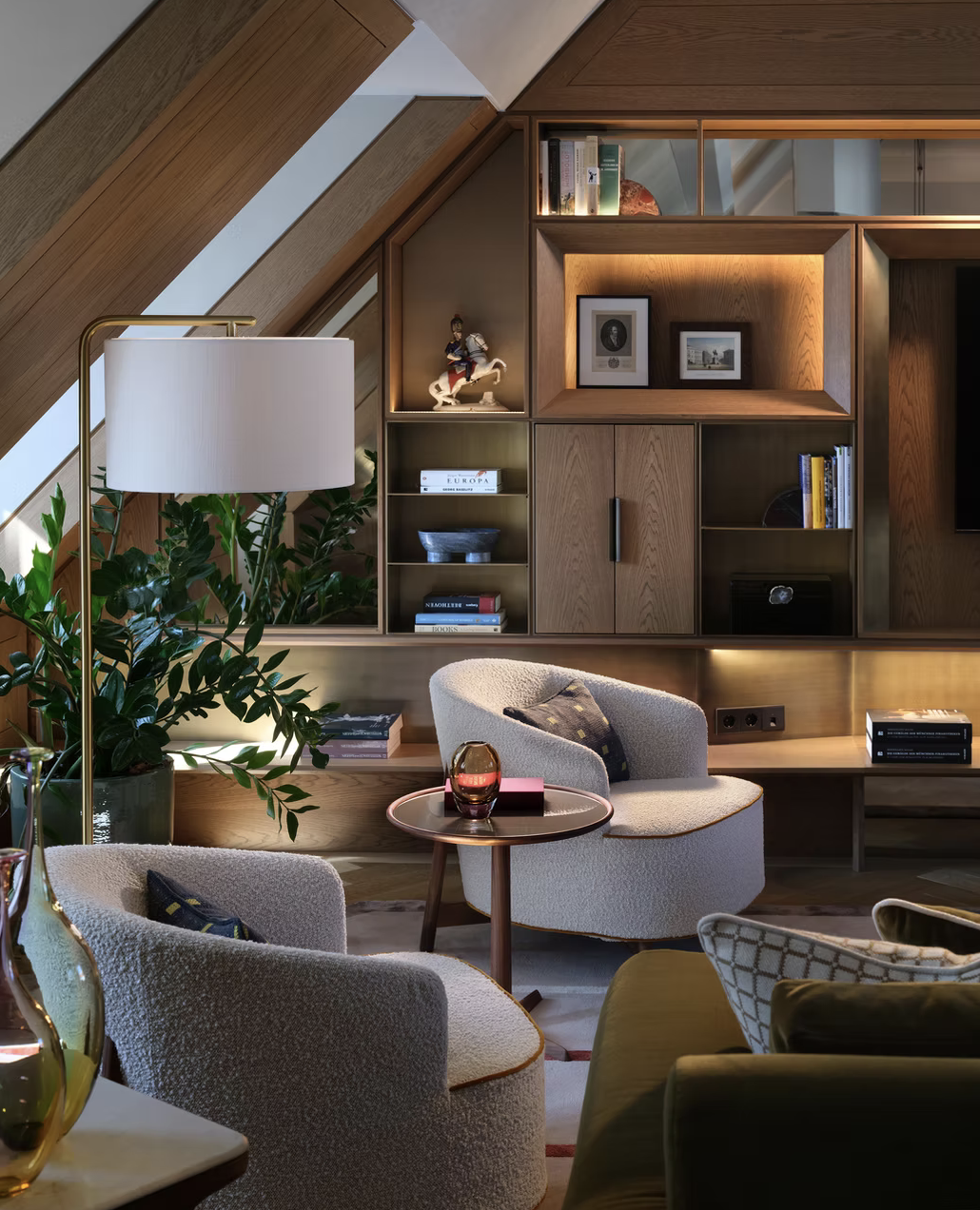 Gemütliches Wohnzimmer mit Holzregalen, Sessel, Stehlampe und Pflanzen.