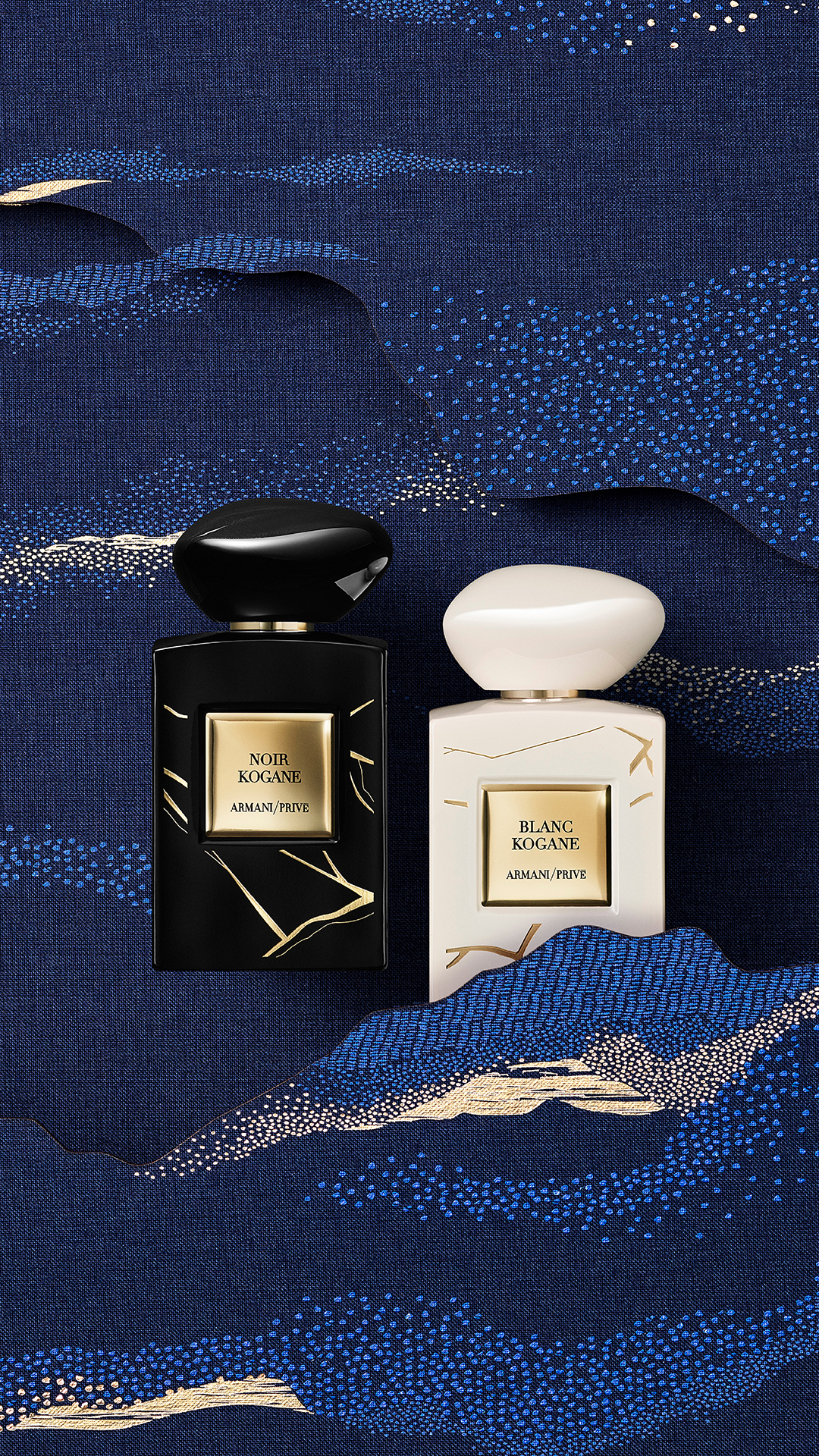 ARMANI Ramadan_Deux flacons de parfum de la marque Armani/Privé, l'un noir nommé 'Noir Kogane' et l'autre blanc nommé 'Blanc Kogane', posés sur un tissu bleu avec un motif de vagues et de nuages dorés et bleus.