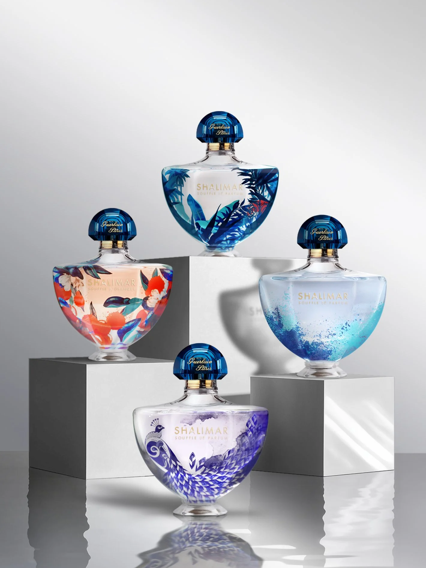 GUERLAIN Shalimar Collection _ Flacons de parfum colorés et illustrés, sont disposés sur des podiums blancs dans un décor minimaliste. Leurs designs sont inspirés de motifs floraux et naturels.
