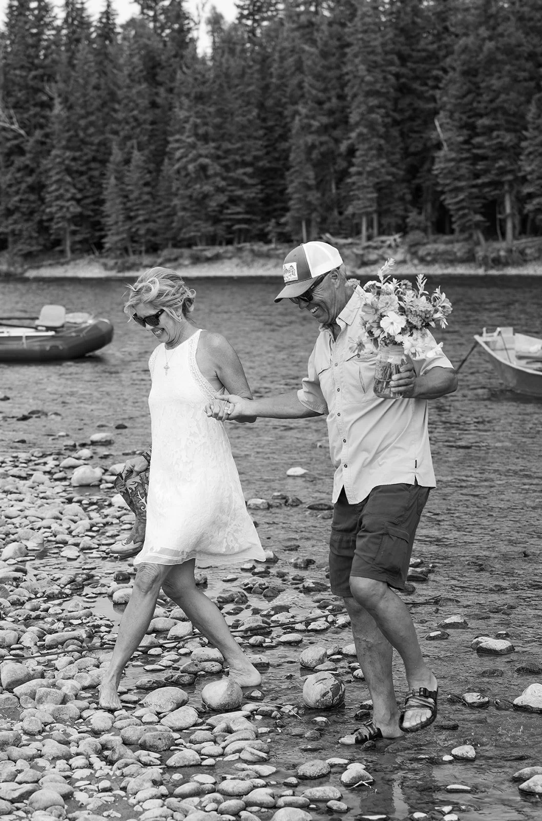 Bride and groom walking ashore hand in hand on the Snake River