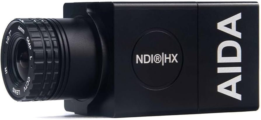 Close-up of an AIDA wireless camera with a black lens and lens markings, and the AIDA logo on the side.