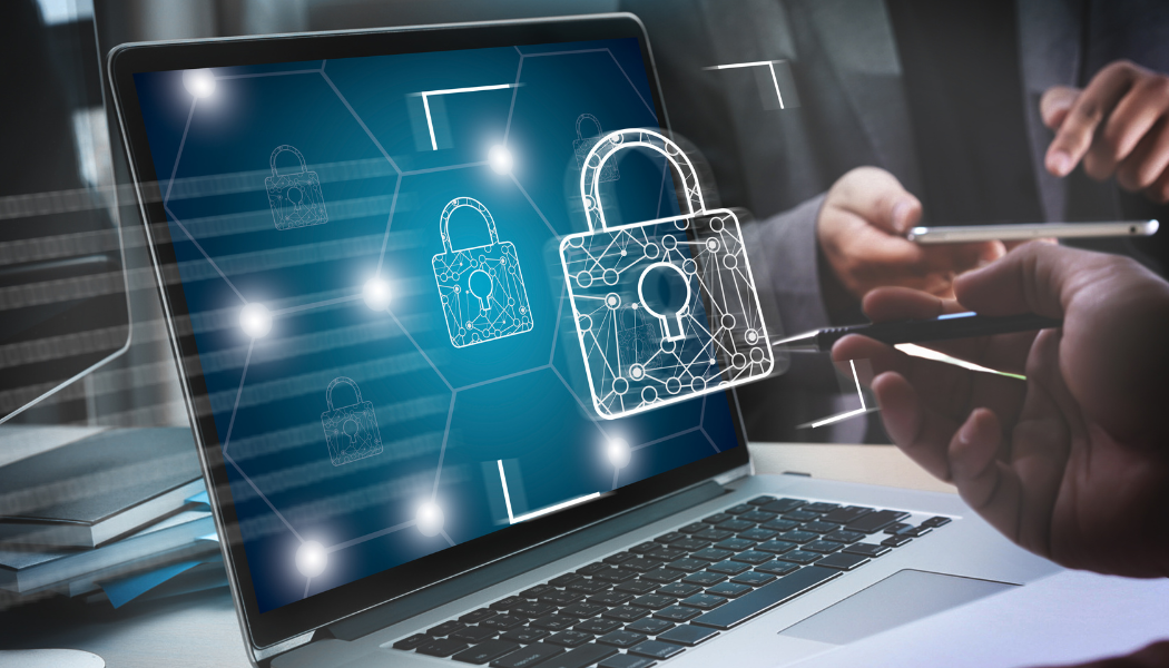 A person holding a stylus and another person holding a smartphone in front of a laptop screen displaying digital padlock icons representing cybersecurity.