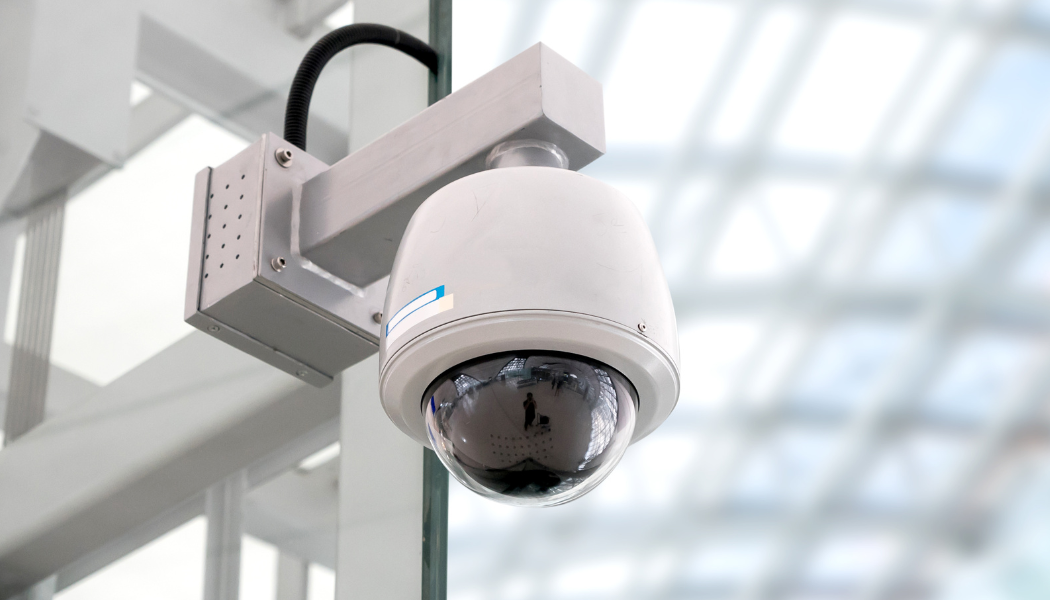 Close-up of a security camera installed on a ceiling in a modern building.
